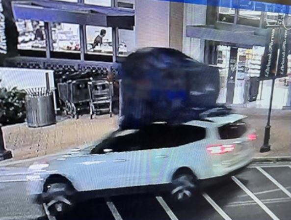 The suspects' white SUV, possibly a Chevy Traverse, with a very large item attached to the roof. (Irvine Police Department)