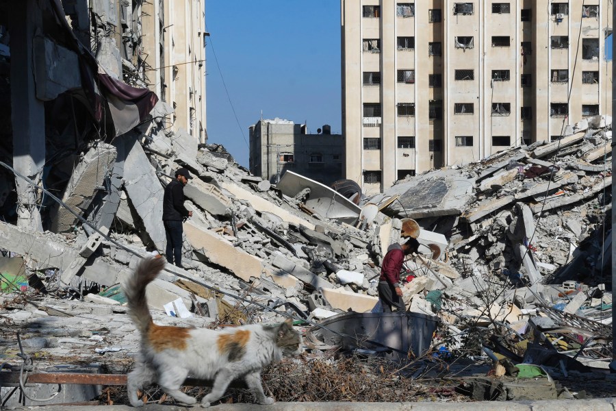 Palestinians walk through destruction from the Israeli bombardment in the Nusseirat refugee camp in Gaza Strip, Friday, Jan. 19, 2024. (AP Photo/Adel Hana)