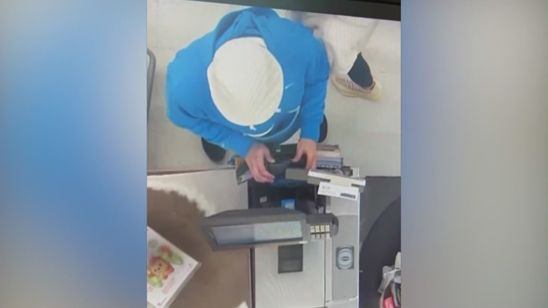 Security footage shows a suspect install a card skimming device on a card reader in a still from an undated video. (Orange County District Attorney's Office)