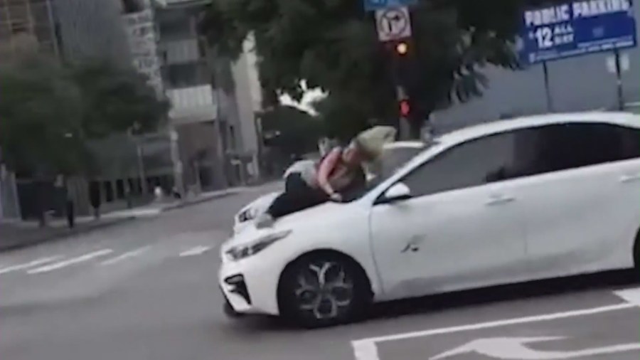 Video captured a woman clinging to the hood of a speeding car as thieves stole her French bulldog puppy in downtown Los Angeles on Jan. 18, 2024. (@harrisonjamesmusic)