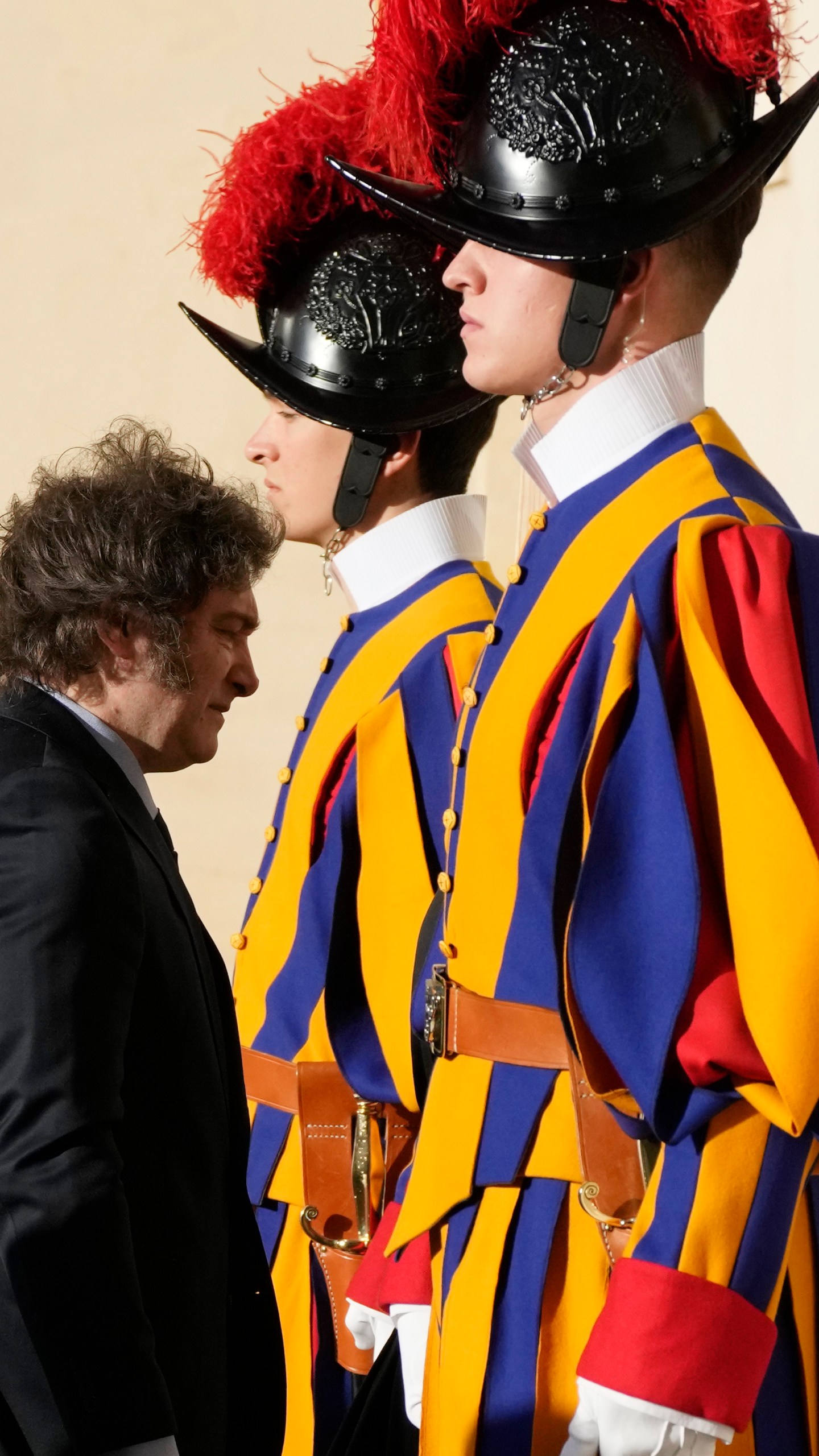 Argentine President Javier Milei walks by two Pontifical Swiss Guards as he arrives in the St. Damasus Courtyard at The Vatican for a private audience with Pope Francis, Monday, Feb. 12, 2024. Milei, who will meet Italian President Sergio Mattarella and Italian Premier Giorgia Meloni later in the day, attended the canonization of the first Argentine female saint, María Antonia de Paz y Figueroa also known as "Mama Antula" in St. Peter's Basilica on Sunday. (AP Photo/Alessandra Tarantino)