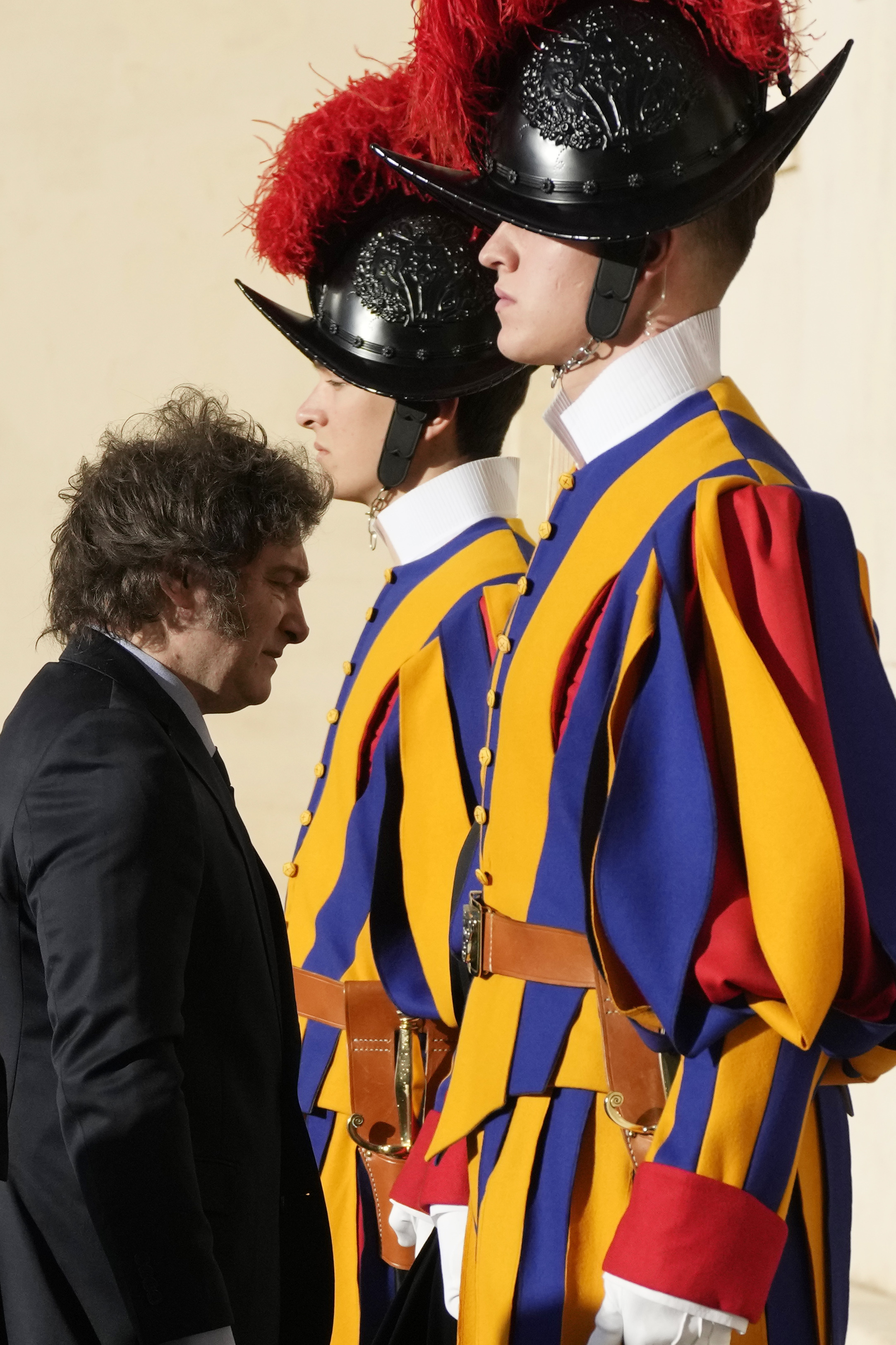 Argentine President Javier Milei walks by two Pontifical Swiss Guards as he arrives in the St. Damasus Courtyard at The Vatican for a private audience with Pope Francis, Monday, Feb. 12, 2024. Milei, who will meet Italian President Sergio Mattarella and Italian Premier Giorgia Meloni later in the day, attended the canonization of the first Argentine female saint, María Antonia de Paz y Figueroa also known as "Mama Antula" in St. Peter's Basilica on Sunday. (AP Photo/Alessandra Tarantino)