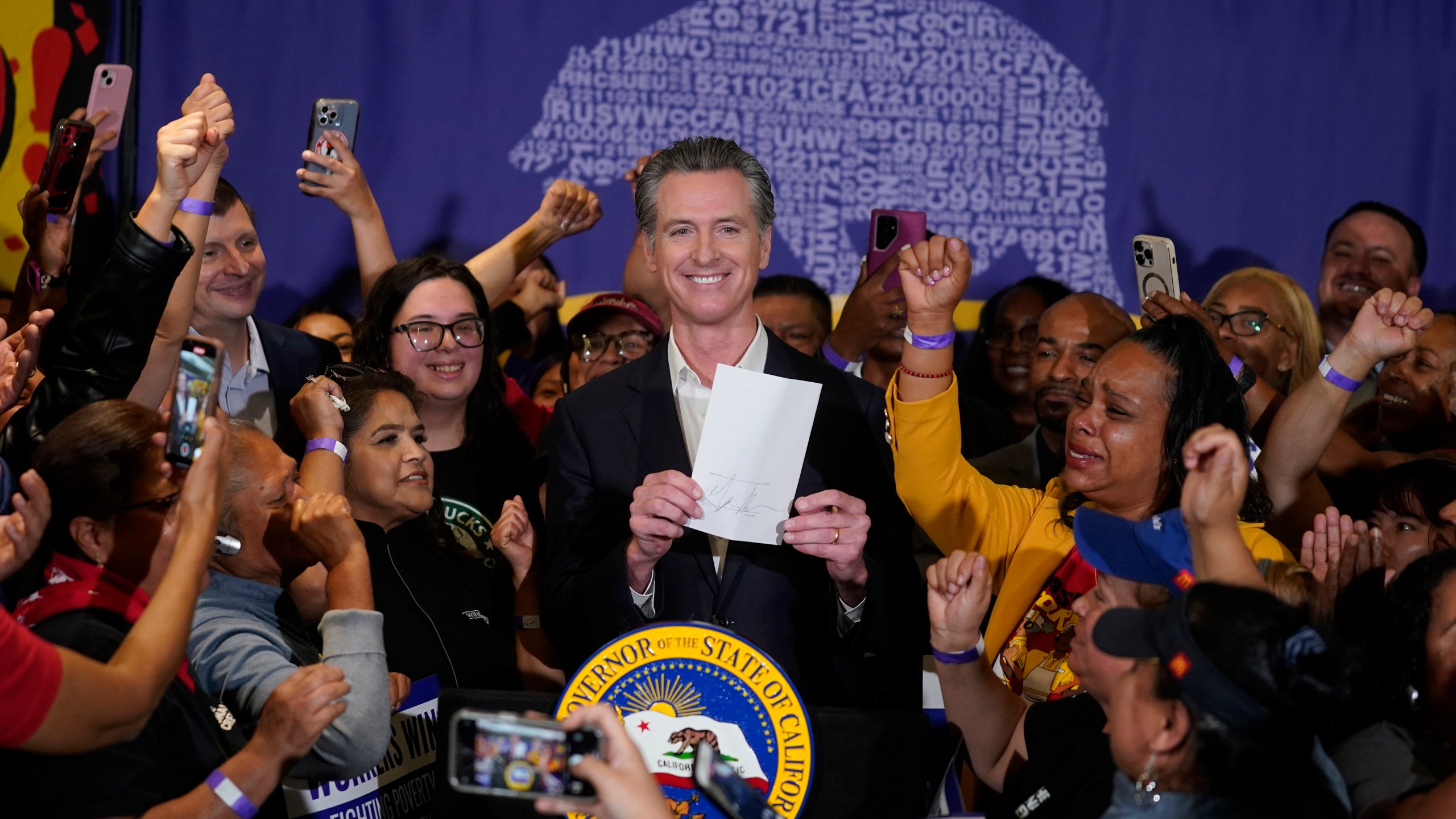 FILE - California Gov. Gavin Newsom signs the fast food bill surrounded by fast food workers at the SEIU Local 721 in Los Angeles, on Thursday, Sept. 28, 2023. Republican leaders in California are calling for an investigation into why a new state law requiring a $20 minimum wage for fast food workers includes an exemption for restaurants like Panera Bread. (AP Photo/Damian Dovarganes, File)