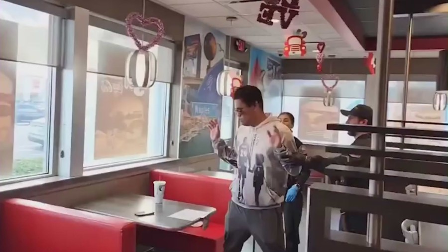 The moment officers chase a suspected child predator through a Carl's Jr. restaurant in Long Beach with the help of “Black Biden,” seen in the red hoodie. (@black_biden8383)