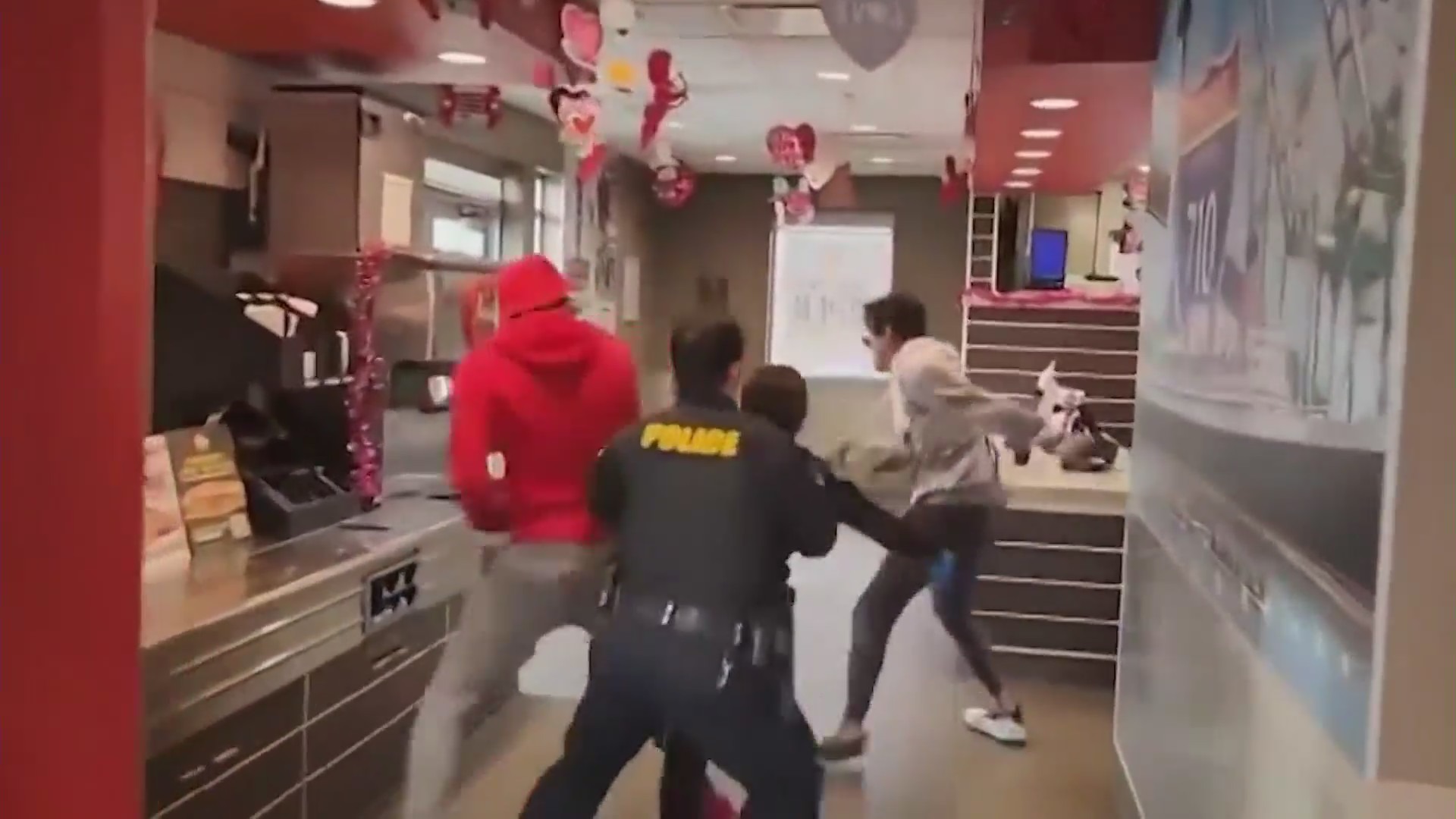 The moment officers chase a suspected child predator through a Carl's Jr. restaurant in Long Beach with the help of “Black Biden,” seen in the red hoodie. (@black_biden8383)