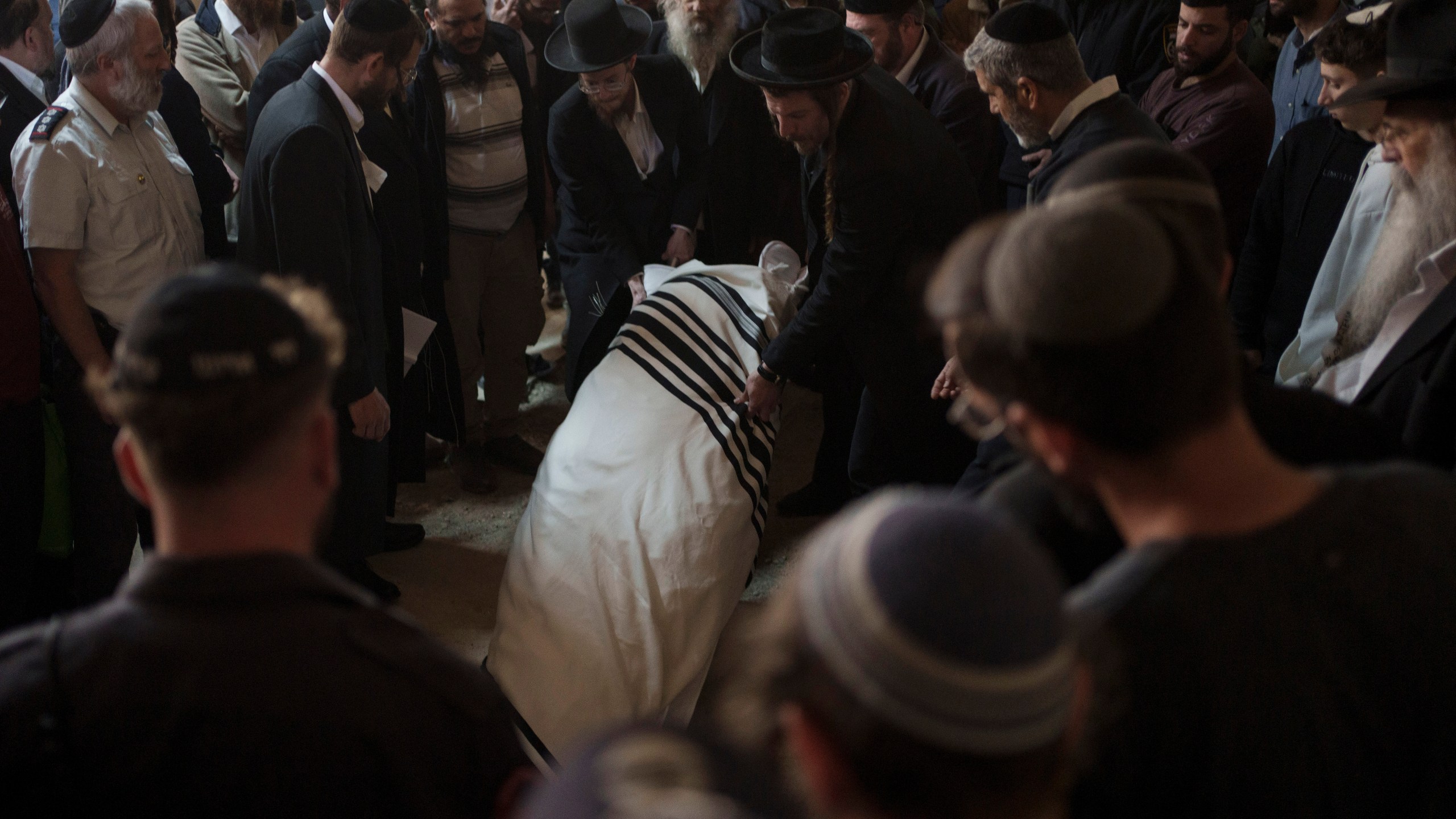 The body of Yitzhak Zeiger is placed in his grave during his funeral at a cemetery in Jerusalem, Israel, Friday, March 1, 2024. Two Israelis, including Zeiger, were killed in a Palestinian shooting attack at a gas station near the Jewish settlement of Eli, in the occupied West Bank on Thursday, the Israeli military said. (AP Photo/Leo Correa)