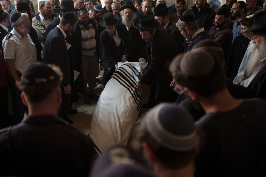 The body of Yitzhak Zeiger is placed in his grave during his funeral at a cemetery in Jerusalem, Israel, Friday, March 1, 2024. Two Israelis, including Zeiger, were killed in a Palestinian shooting attack at a gas station near the Jewish settlement of Eli, in the occupied West Bank on Thursday, the Israeli military said. (AP Photo/Leo Correa)