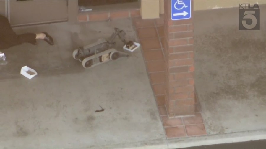 A remote-controlled robot and drone investigate possible suspicious devices near the suspect on March 26, 2024. (KTLA)