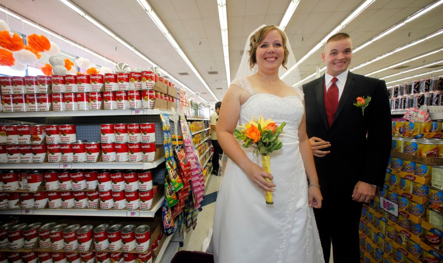 US Marine Whillis Hall, Jr. right, and bride Emily Wiley, react after getting married along other nine couples at the 99 Cent store in the Hollywood section of Los Angeles on Wednesday, Sep. 09, 2009. The discount chain will send the couples off in a limousine, with $99.99 in cash, and take them to an undisclosed "famous romantic Los Angeles" spot. All nine couples who got married in the store also will get a free night's stay, including dinner, at the Hotel Angeleno. (AP Photo/Damian Dovarganes)