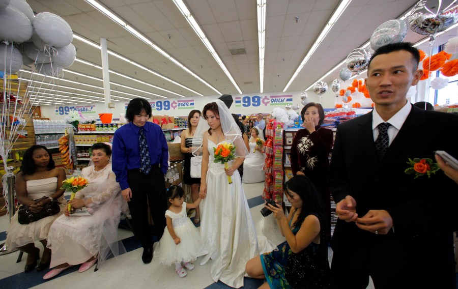 Groom Jon Nguyen, far right, and his bride, Bonnie Cam, middle, holding their daughter, Autumn, wait with other couples to be married at the 99 Cent store in the Hollywood section of Los Angeles on Wednesday, Sep. 09, 2009. The discount chain will send the couples off in a limousine, with $99.99 in cash, and take them to an undisclosed "famous romantic Los Angeles" spot. All nine couples who got married in the store also will get a free night's stay, including dinner, at the Hotel Angeleno. Other people are not identified. (AP Photo/Damian Dovarganes)