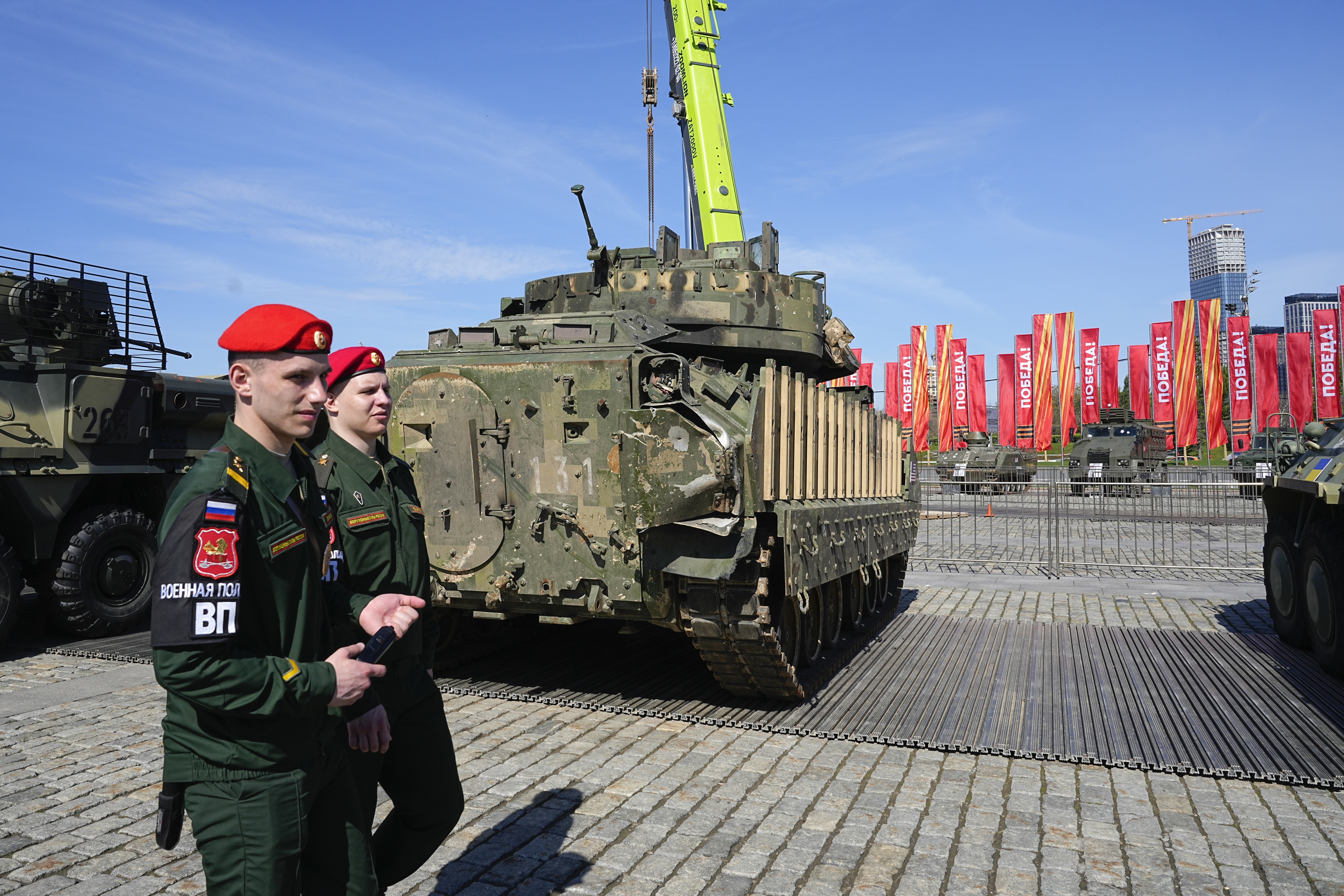 Russian military police soldiers walk past a M2A2 Bradley Fighting Vehicle that belonged to the Ukrainian army on display in Moscow, Tuesday, April 30, 2024. The Russian military put some of the equipment captured from Ukrainian forces on display in Moscow. (AP Photo/Alexander Zemlianichenko)