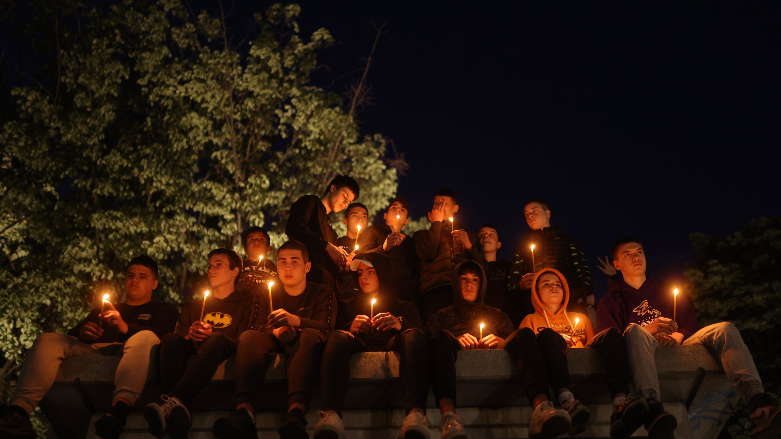 FILE - People hold candles for the victims near the Vladislav Ribnikar school in Belgrade, Serbia, Wednesday, May 3, 2023. A teenage boy opened fire at the school on the morning of May 3, 2023. Eight children and a school guard died, and seven people were wounded. One of the wounded, a child, died from injuries later. A total of 10 people were killed. (AP Photo/Armin Durgut, File)