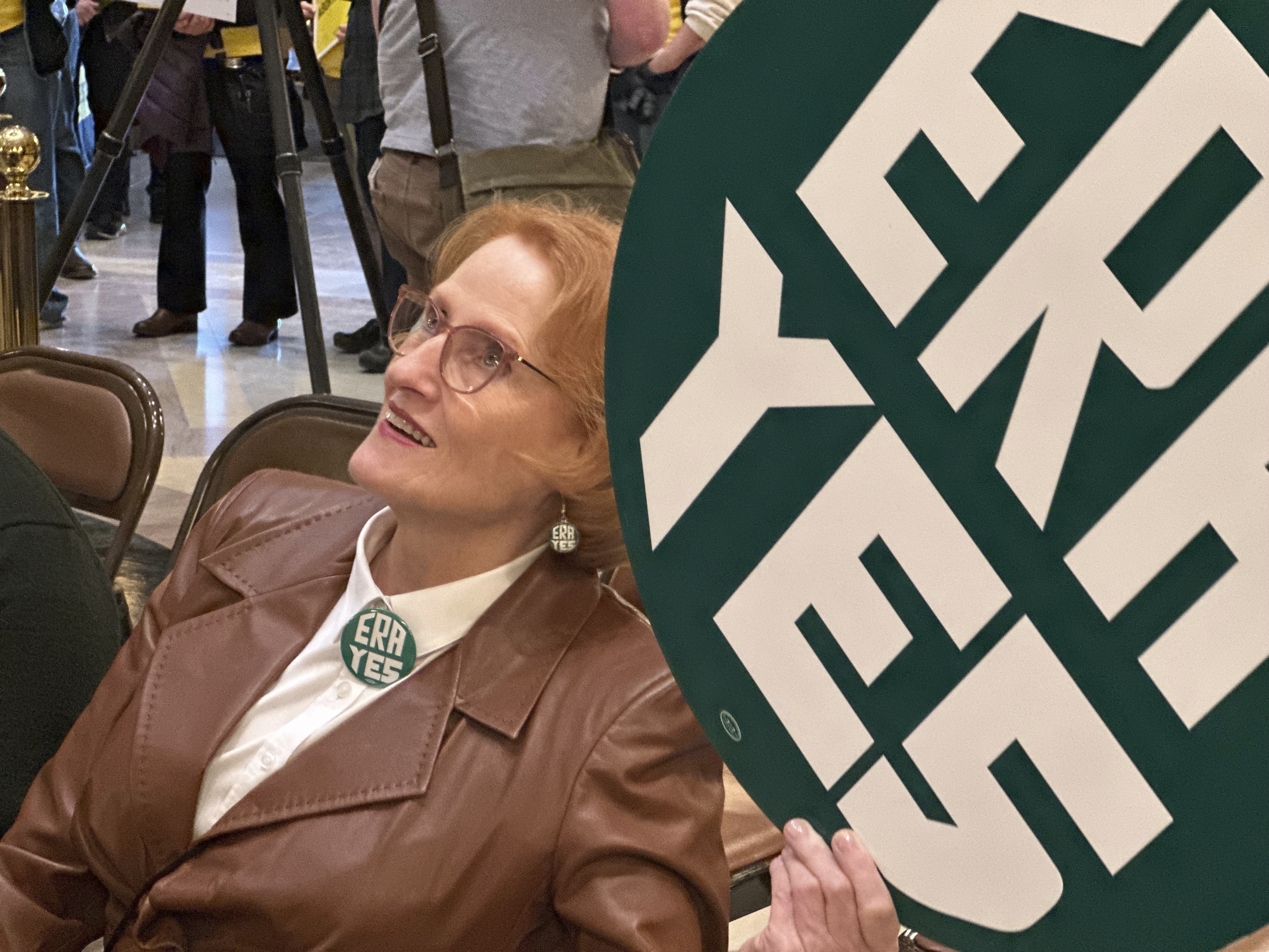 CORRECTS PHOTOGRAPHER TO STEVE KARNOWSKI - Betty Folliard, an advocate for the proposed Minnesota Equal Rights Amendment and the founder of ERA Minnesota, holds a green sign that says "ERA YES" during a rally in support of the proposal, March 7, 2024, in the Capitol building in St. Paul, Minn. The proposal would be among the most expansive protections of women's rights, abortion rights and LGBTQ rights in the nation if it is approved by lawmakers this session and then by Minnesota voters on the 2026 ballot. (AP Photo/Steve Karnowski)