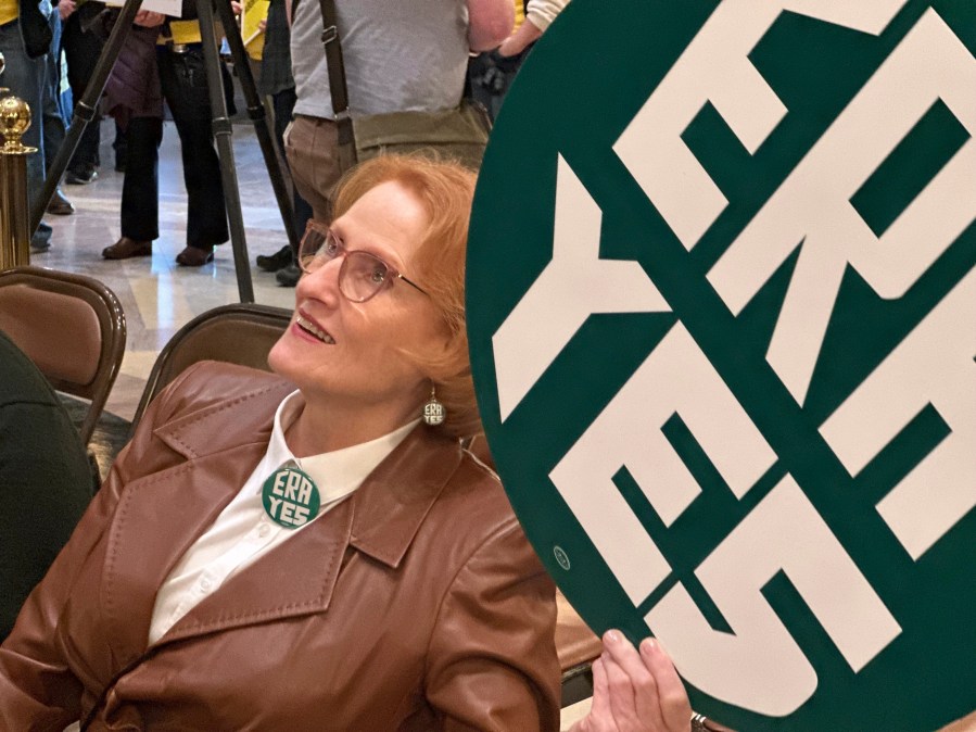 CORRECTS PHOTOGRAPHER TO STEVE KARNOWSKI - Betty Folliard, an advocate for the proposed Minnesota Equal Rights Amendment and the founder of ERA Minnesota, holds a green sign that says "ERA YES" during a rally in support of the proposal, March 7, 2024, in the Capitol building in St. Paul, Minn. The proposal would be among the most expansive protections of women's rights, abortion rights and LGBTQ rights in the nation if it is approved by lawmakers this session and then by Minnesota voters on the 2026 ballot. (AP Photo/Steve Karnowski)