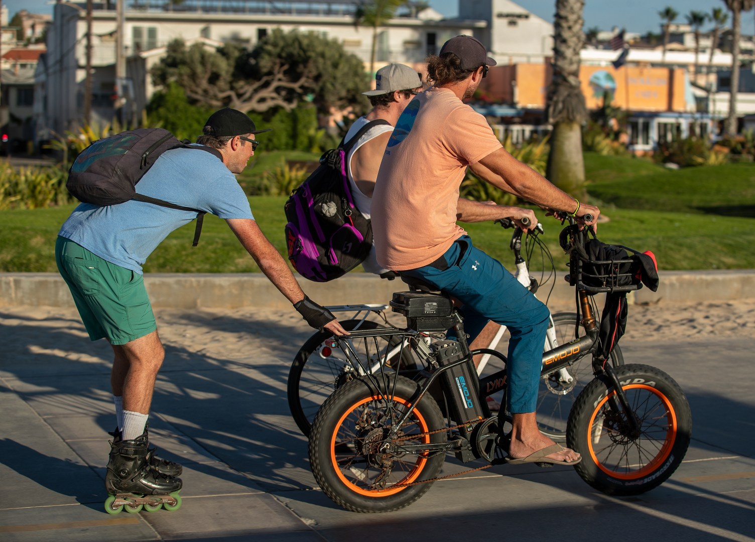 HERMOSA BEACH, CA-NOVEMBER 10, 2023, 2023:A roller blader hitches a ride on the back of an e-bike, while on the Strand in Hermosa Beach. In Hermosa Beach, it's against city code to use electric power on the Strand, but many e-bike riders do so anyway. (Mel Melcon / Los Angeles Times via Getty Images)