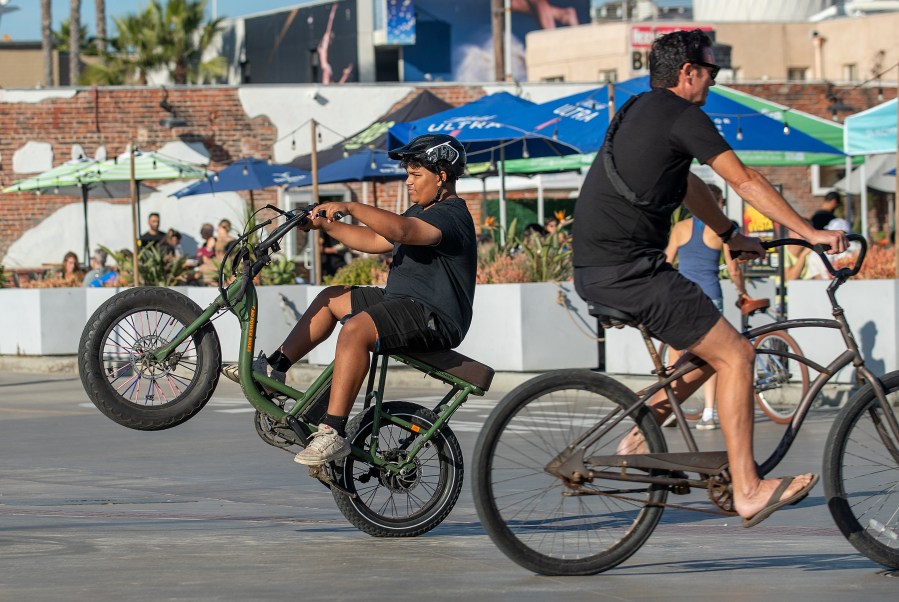 HERMOSA BEACH, CA-NOVEMBER 10, 2023, 2023:A boy rides his e-bike on the Strand in Hermosa Beach. In Hermosa Beach, it's against city code to use electric power on the Strand, but many e-bike riders do so anyway.  (Mel Melcon / Los Angeles Times via Getty Images)