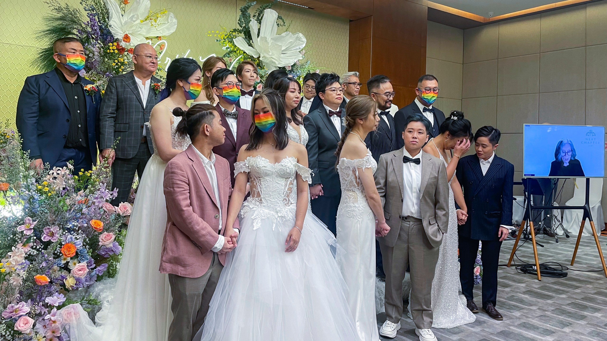 Ten same-sex couples who got married in the United States over the internet stand during their wedding at Eaton Hotel, Kowloon, Hong Kong, Tuesday, June 25, 2024. The semi-autonomous southern Chinese city does not formally recognize such unions but offers them legal protections. The event Tuesday was timed to mark Pride Month. (AP Photo/Alice Fung)