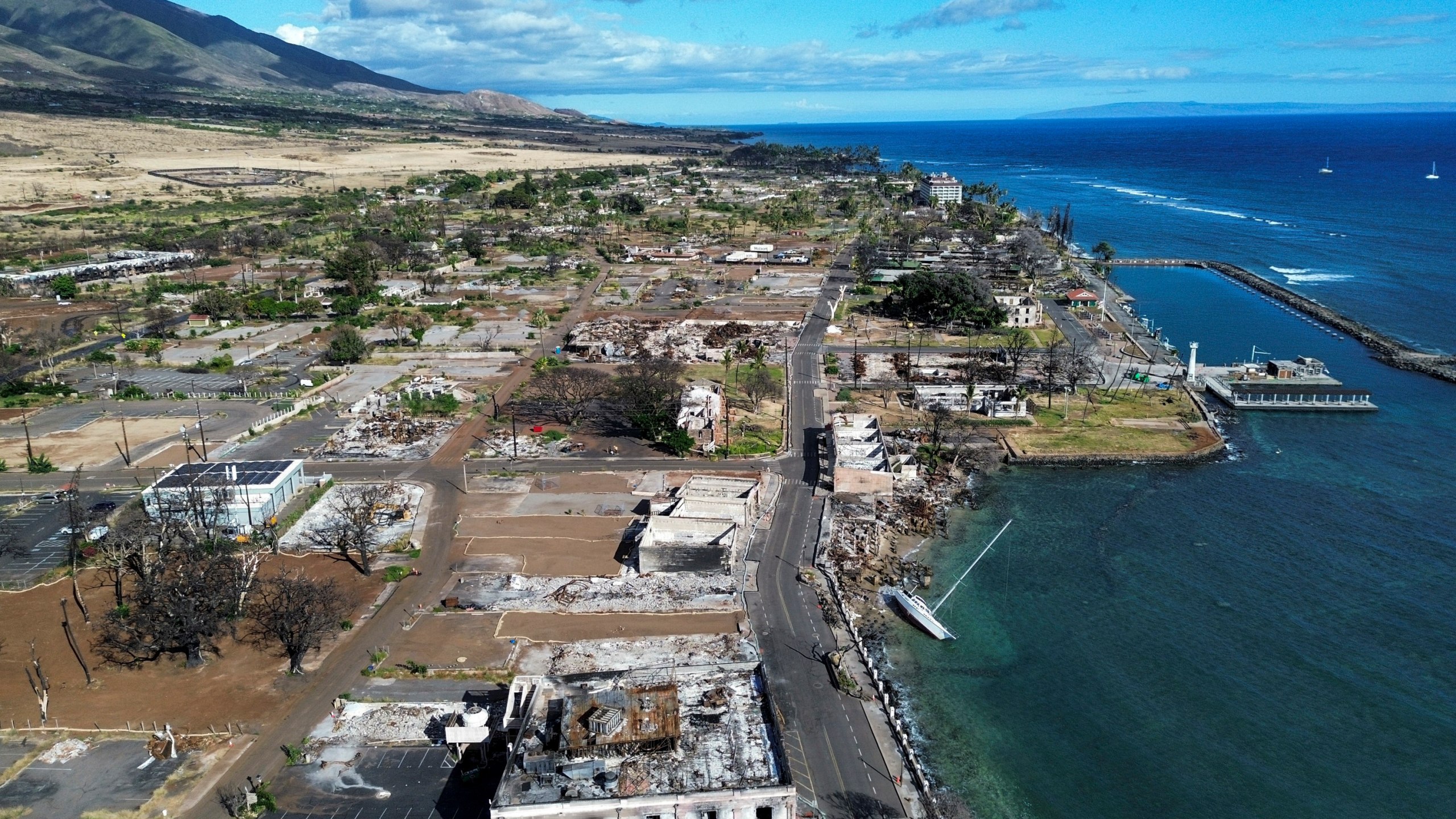 A general view of Front Street shows the primary debris from last year's wildfire being removed for commercial properties, Wednesday, June 26, 2024, in Lahaina, Hawaii. (AP Photo/Mengshin Lin)