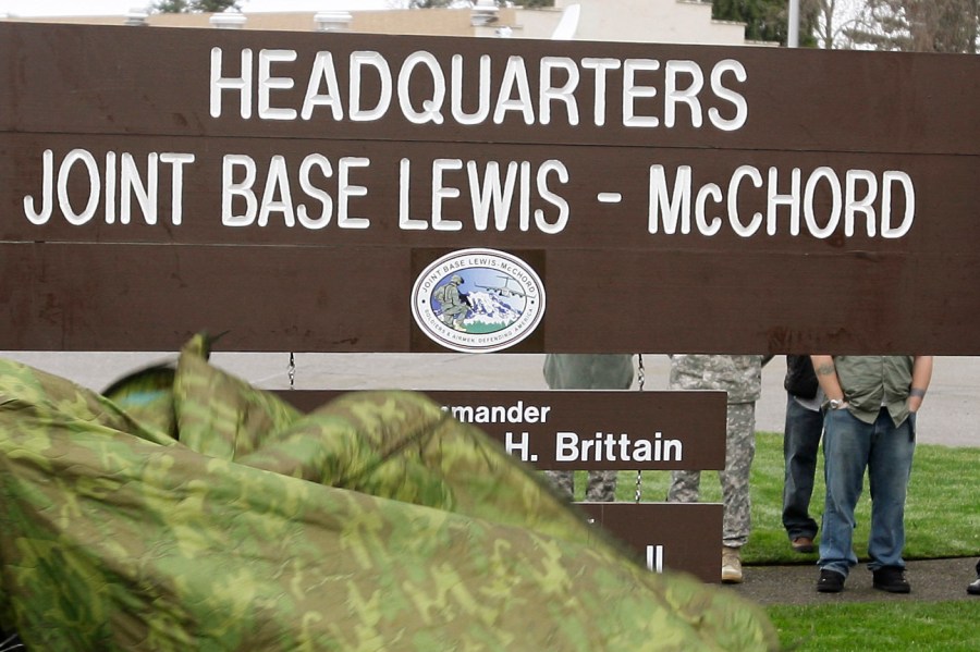 FILE - A new sign is unveiled during a ceremony marking the initial operational capability of the merger of Fort Lewis and McChord Air Force Base into Joint Base Lewis-McChord, Monday, Feb. 1, 2010, in Washington state. Fifteen current or retired Joint Base Lewis-McChord servicemen who say the Army failed to protect them from a military doctor who's been charged with sexual abuse are seeking $5 million in damages for the emotional distress they say they've suffered. (AP Photo/Ted S. Warren, File)
