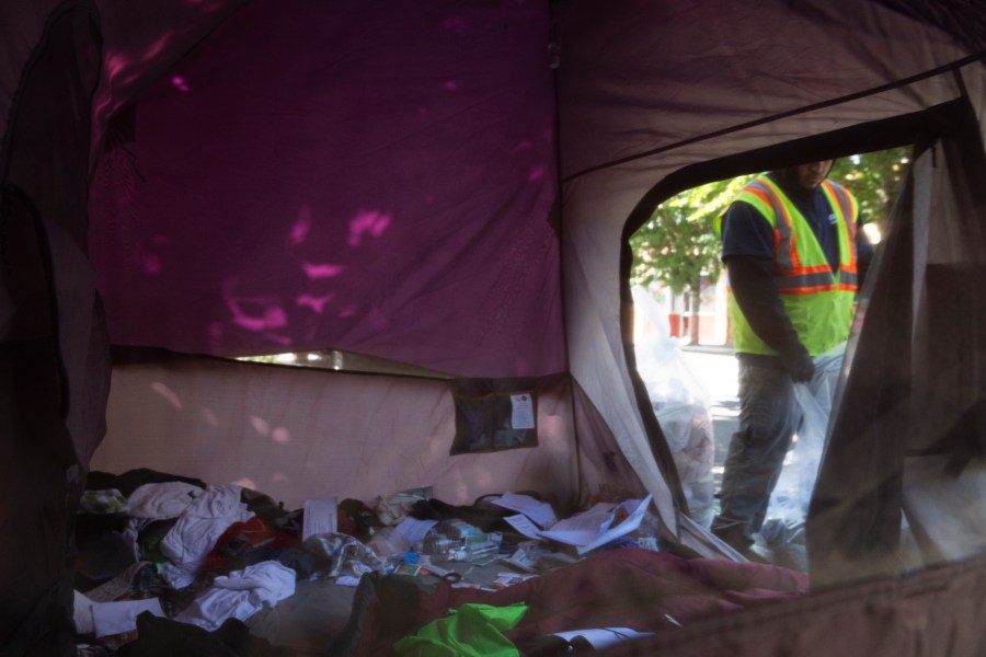 Workers remove contents from a tent after Portland police detained the homeless person residing there on Friday, June 28, 2024, in Portland, Ore. Authorities removed two tents on the sidewalk outside Lan Su Chinese Garden. The Supreme Court cleared the way for cities to enforce bans on homeless people sleeping outside in public places on Friday, overturning a ruling from a California-based appeals court that found such laws amount to cruel and unusual punishment when shelter space is lacking. (AP Photo/Jenny Kane)
