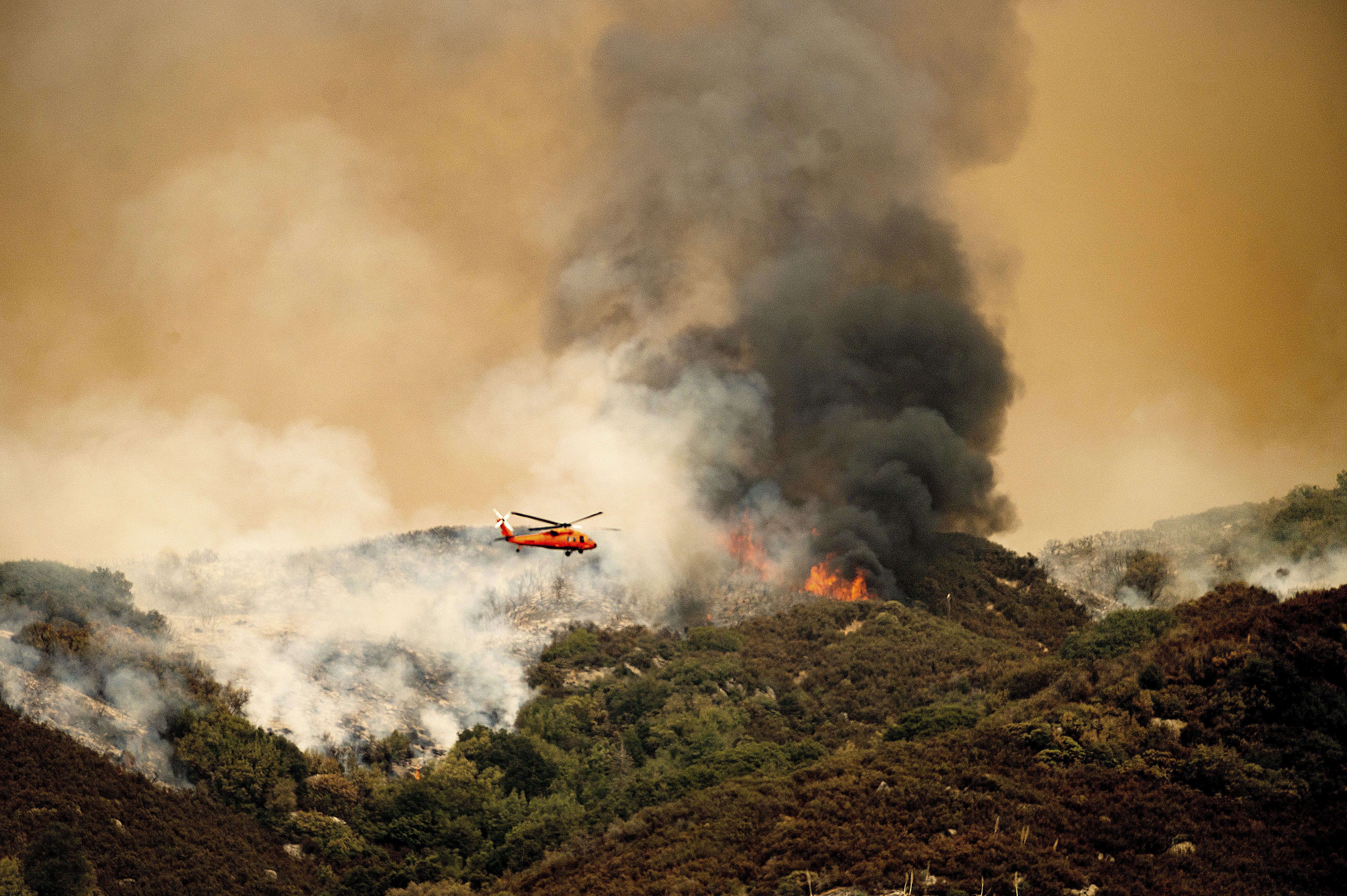 A helicopter prepares to drop water on the KNP Complex Fire in Sequoia National Park, Calif., on Sept. 15, 2021. Fire managers declared the KNP Complex 100% contained on Thursday, Dec. 16 the National Park Service said Friday, Dec. 17. (AP Photo/Noah Berger, File)