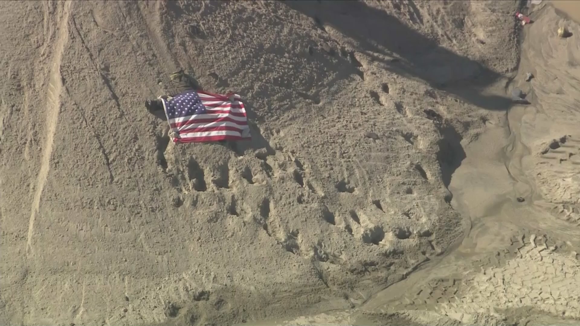 A body was seen covered by an American flag after a deadly explosion near Palmdale on June 14, 2024. (KTLA)