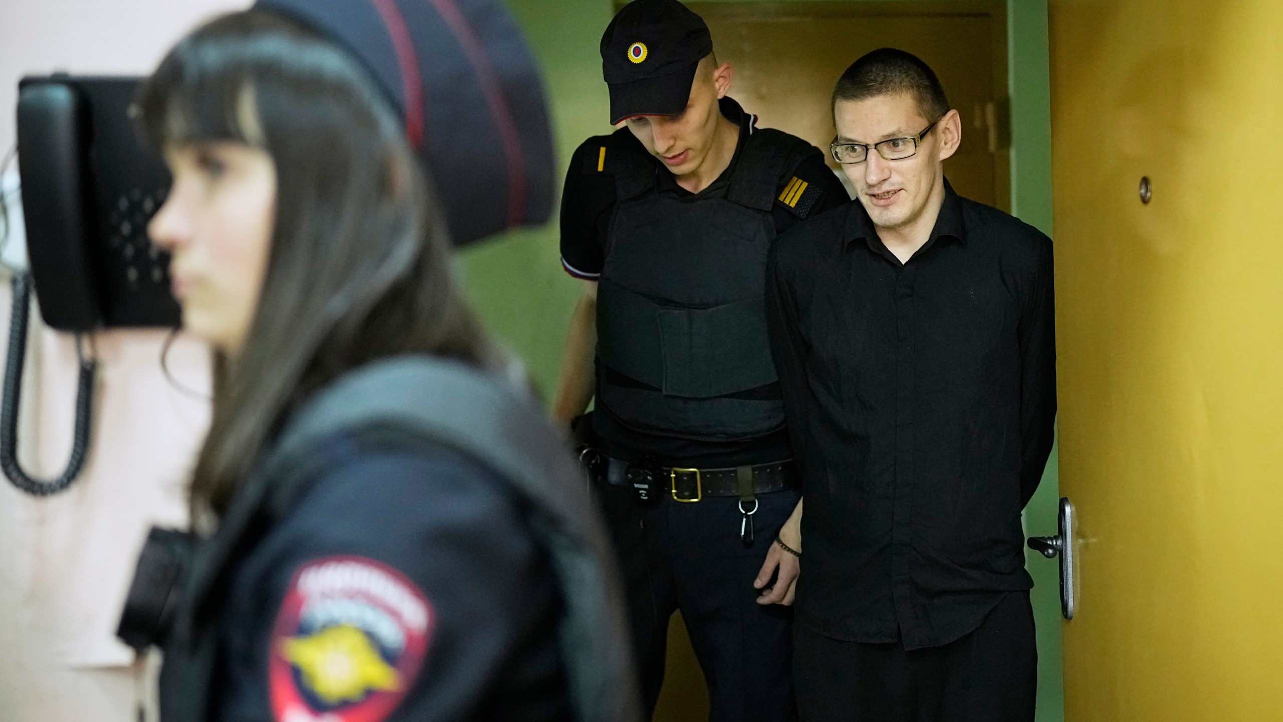 Robert Woodland, right, a Russia-born U.S. citizen, is escorted to the courtroom for a hearing, Thursday, July 4, 2024, in Moscow, Russia. Woodland was convicted of drug-related charges and sentenced to 12 and a 1/2 years in prison on Thursday. (AP Photo/Alexander Zemlianichenko)