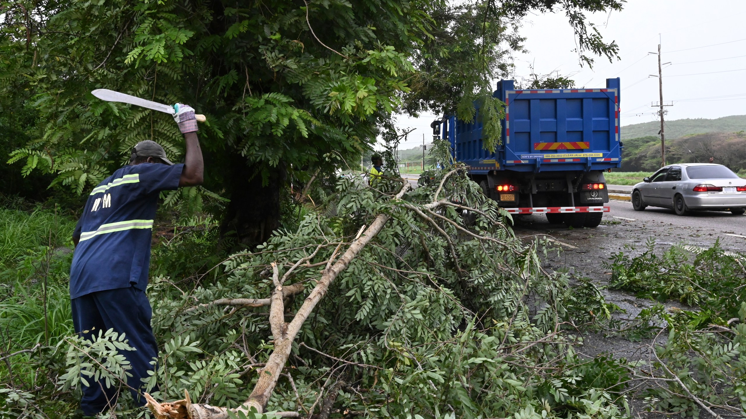 Workers remove trees branches felled by Hurricane Beryl in Kingston, Jamaica, Thursday, July 4, 2024. What had been the earliest storm to develop into a Category 5 hurricane in the Atlantic, weakened to a Category 3 by early Thursday but remained a major hurricane taking aim at Mexico’s Caribbean coast. (AP Photo/Collin Reid)