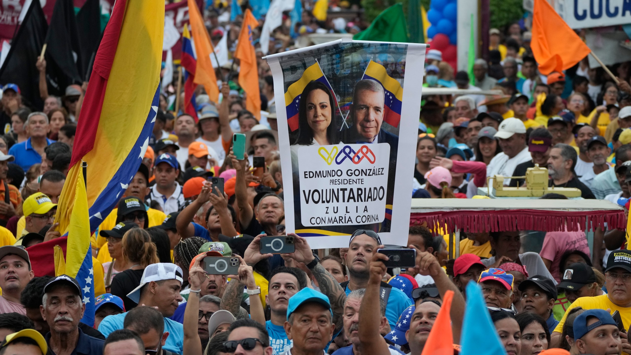 FILE - A supporter holds up a banner with images of opposition leader Maria Corina Machado and presidential candidate Edmundo Gonzalez, during a campaign rally in Maracaibo, Venezuela Thursday, May 2, 2024. No decision in Venezuela over the past 25 years has been as consequential as the choice voters will make on July 28. (AP Photo/Ariana Cubillos, File)