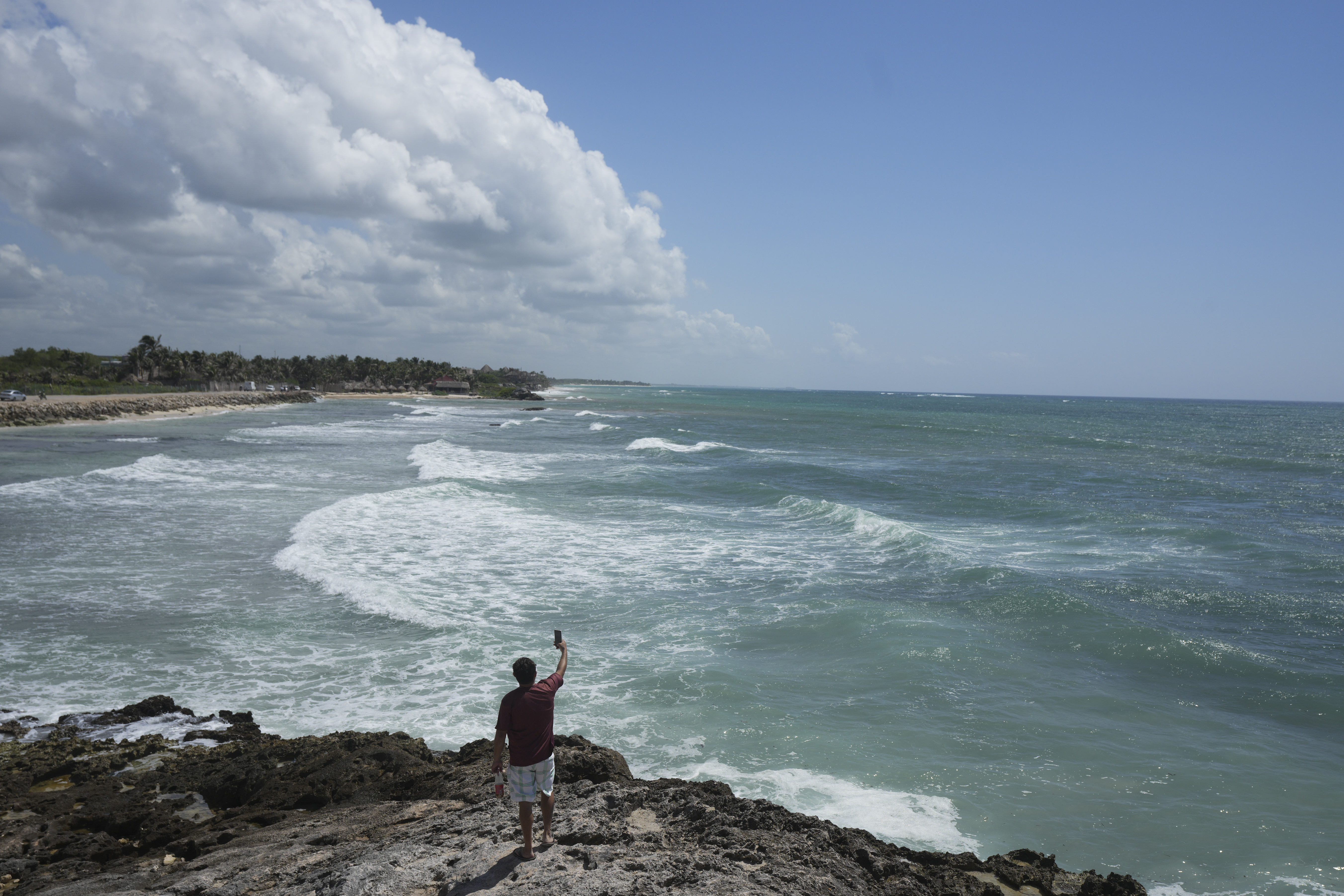 A man takes a video from the rocky shore of Mirador beach ahead of Hurricane Beryl's expected arrival, in Tulum, Mexico, Thursday, July 4, 2024. (AP Photo/Fernando Llano)