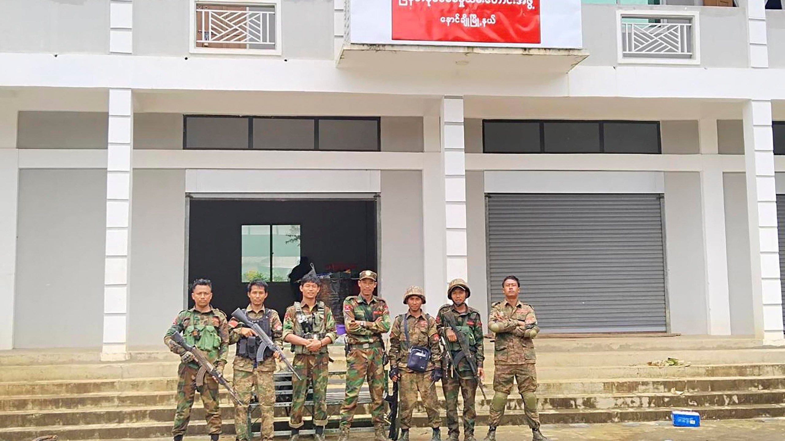 In this handout photo provided by Mandalay People's Defence Force, members of the Ta'ang National Liberation Army, one of the ethnic armed forces in the Brotherhood Alliance, and the Mandalay People's Defence Force pose for a photograph in front of the captured building of the Myanmar War Veterans' Organisation in Nawnghkio township in Shan state, Myanmar, June 26, 2024. New fighting has broken out in northeastern Myanmar, bringing an end to a Chinese-brokered cease-fire and putting pressure on the military regime as it faces attacks from resistance forces on multiple fronts in the country's civil war. (Mandalay People's Defence Force via AP)