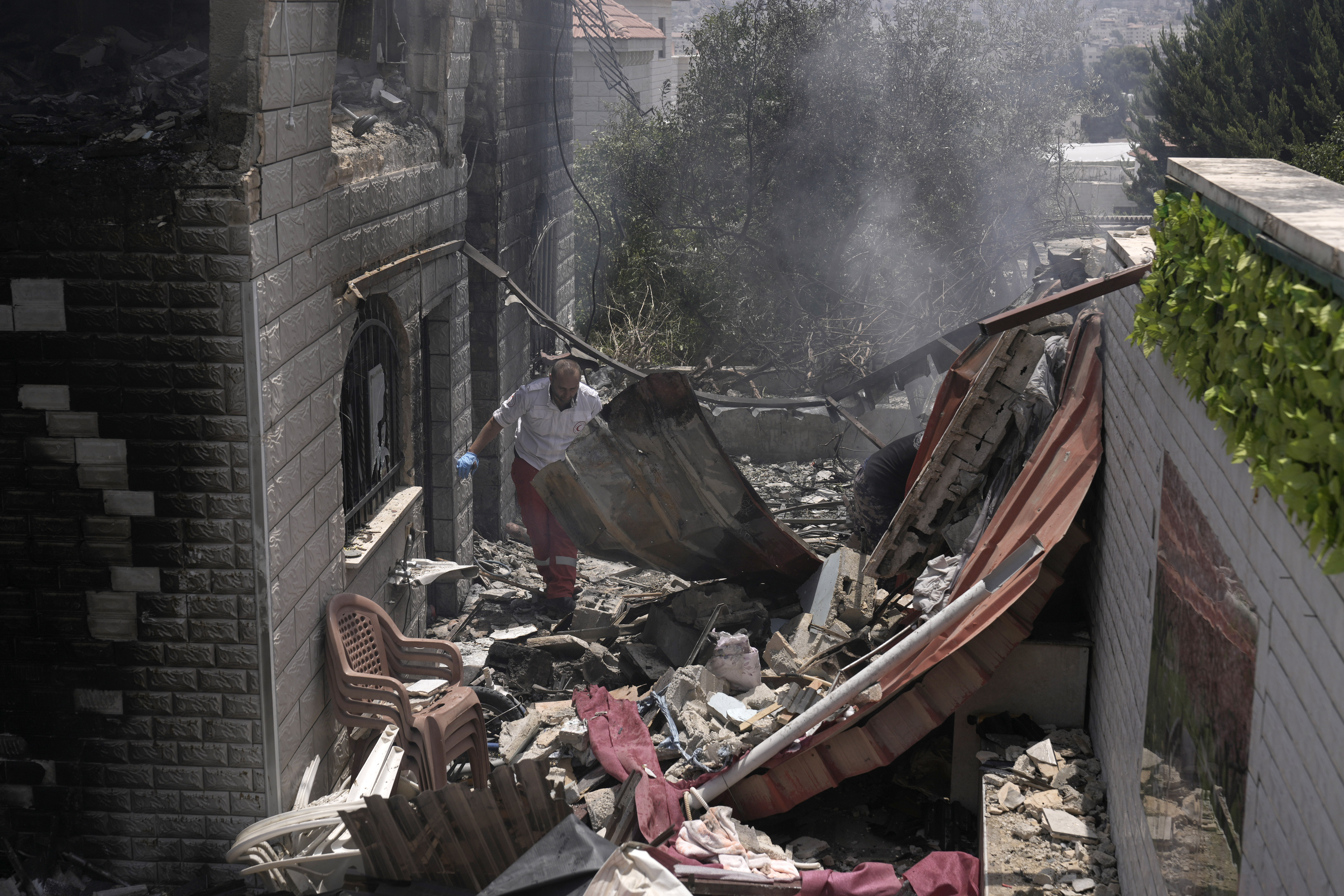 A Palestinian first responder navigates the rubble of a home destroyed in an Israeli military operation in the West Bank city of Jenin, Friday, July 5, 2024. The Israeli military said Friday it was conducting counterterrorism activity that included an airstrike in the area of the West Bank city of Jenin. Palestinian authorities said five people were killed. (AP Photo/Majdi Mohammed)