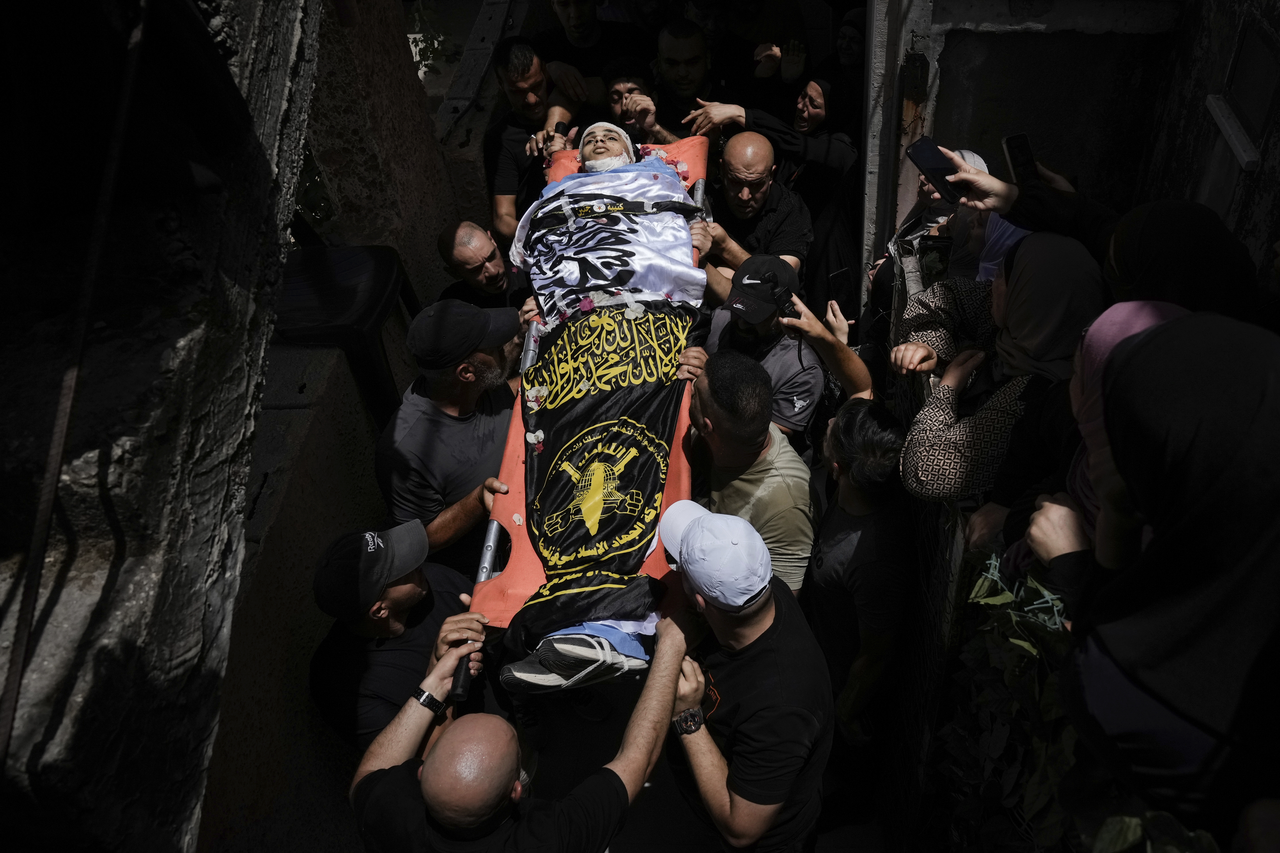 Mourners carry the body of Ahmed Amouri, draped in Palestinian Islamic Jihad militant group flags, during his funeral after he was killed in an Israeli military operation, in Jenin refugee camp in the West Bank city of Jenin, Friday, July 5, 2024. Palestinian authorities say seven people were killed Friday during an Israeli military operation in the area of the West Bank city of Jenin, where the Israeli military said it had been carrying out “counterterrorism activity” that included an airstrike. (AP Photo/Majdi Mohammed)