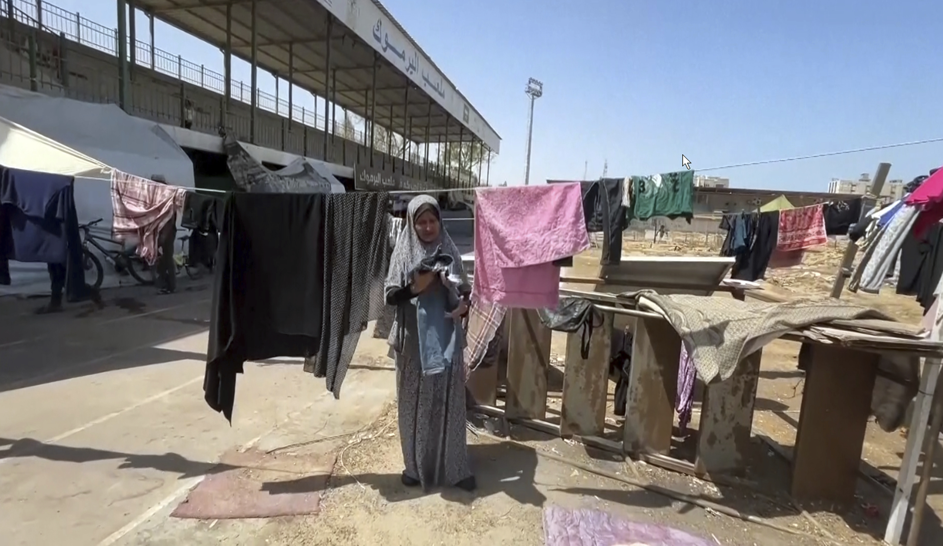 This image from video shows a woman drying clothes, Friday, July 5, 2024 in Gaza City, Gaza Strip. Yarmouk Sports Stadium, once Gaza's biggest soccer arena, is now sheltering thousands of displaced Palestinians who are scraping by with little food or water. (AP Photo)