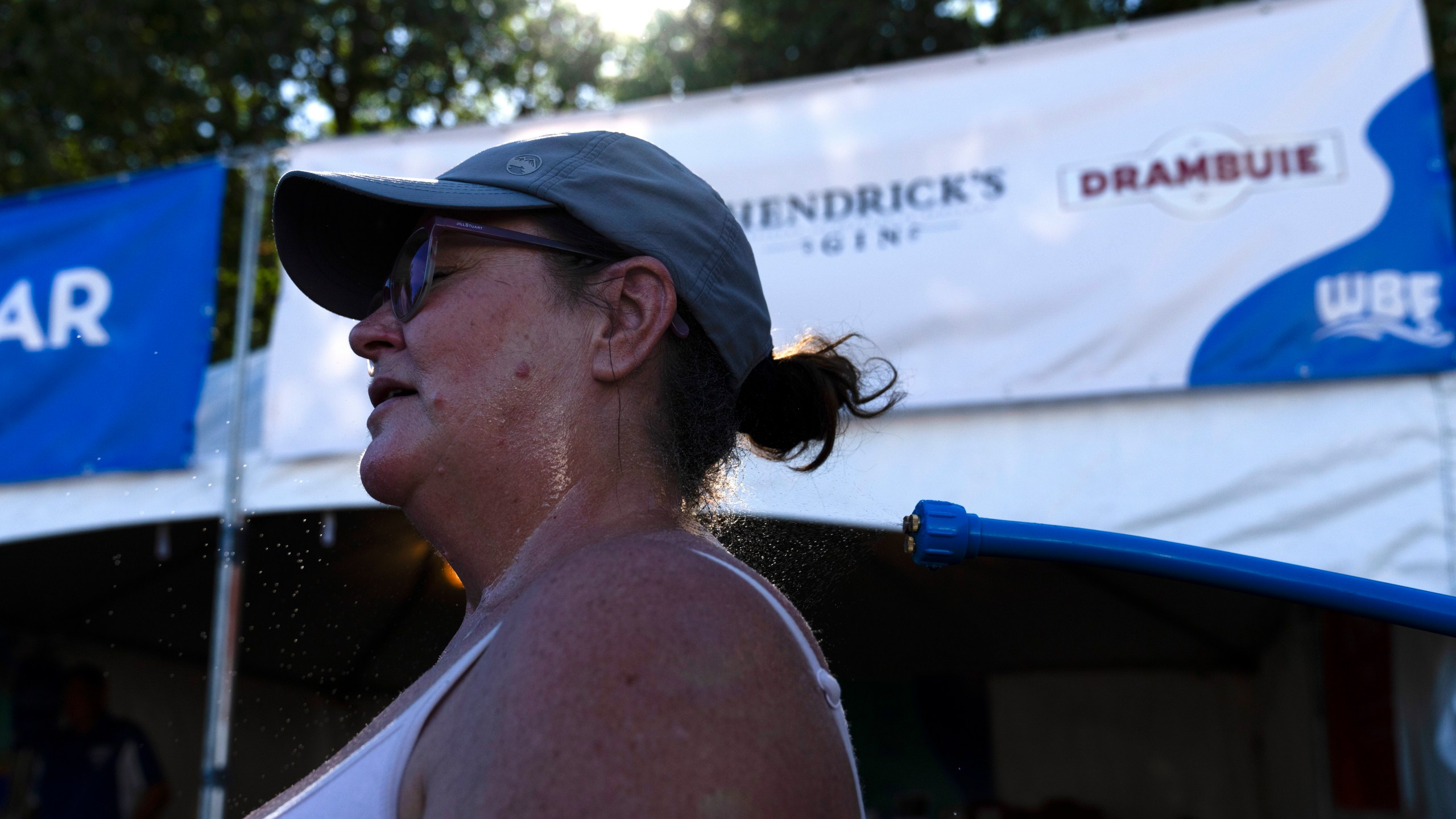 Gina Rowlett uses the mister to cool off at the Waterfront Blues Festival on Friday, July 5, 2024, in Portland, Ore. A slow-moving and potentially record-setting heat wave is spreading across the Western U.S., sending many residents in search of a cool haven from the dangerously high temperatures. (AP Photo/Jenny Kane)