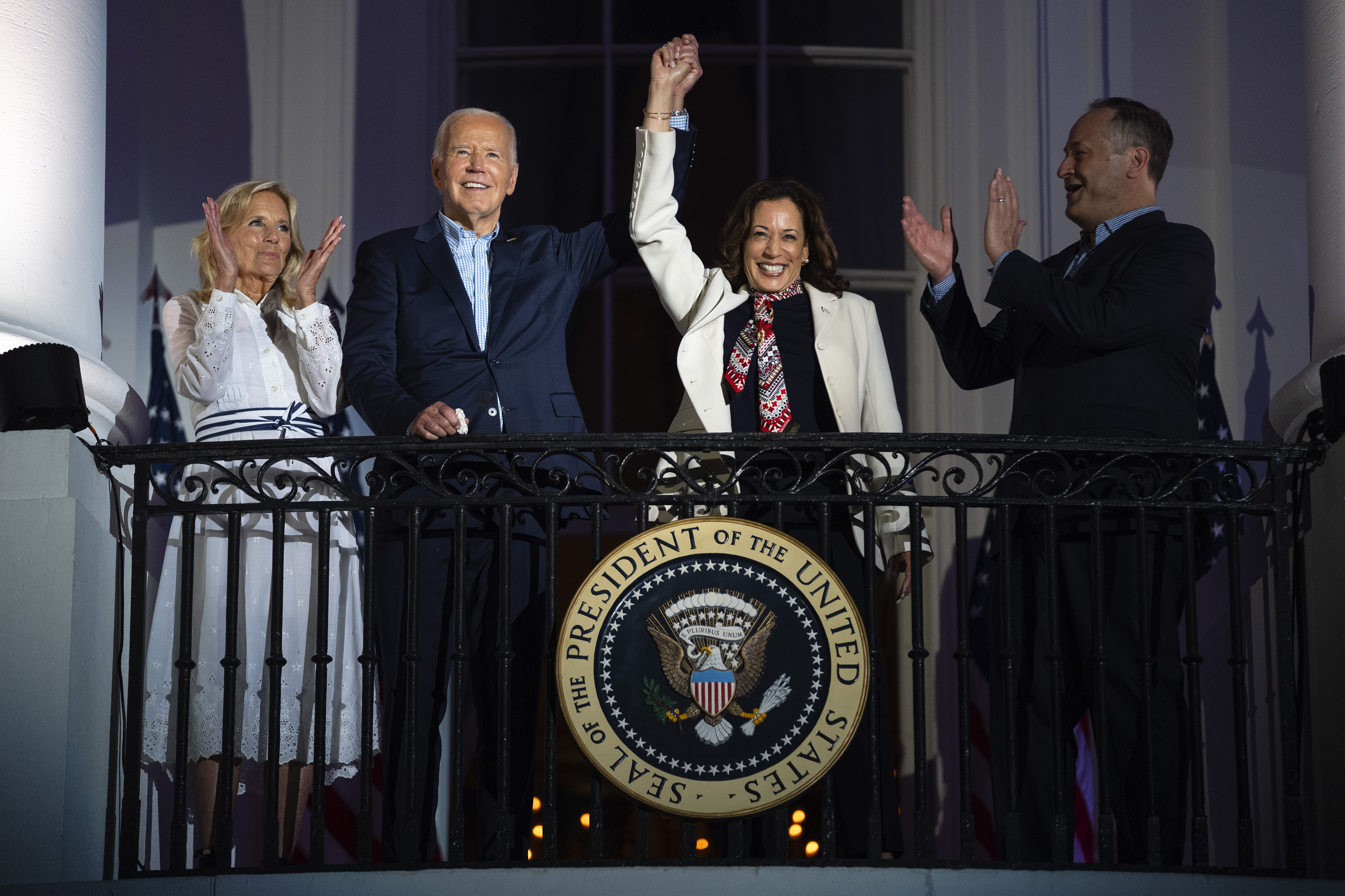 First lady Jill Biden and second gentleman Douglass Emhoff watch as President Joe Biden raises the hand of Vice President Kamala Harris as they view the Independence Day firework display over the National Mall from the balcony of the White House, Thursday, July 4, 2024, in Washington. (AP Photo/Evan Vucci)