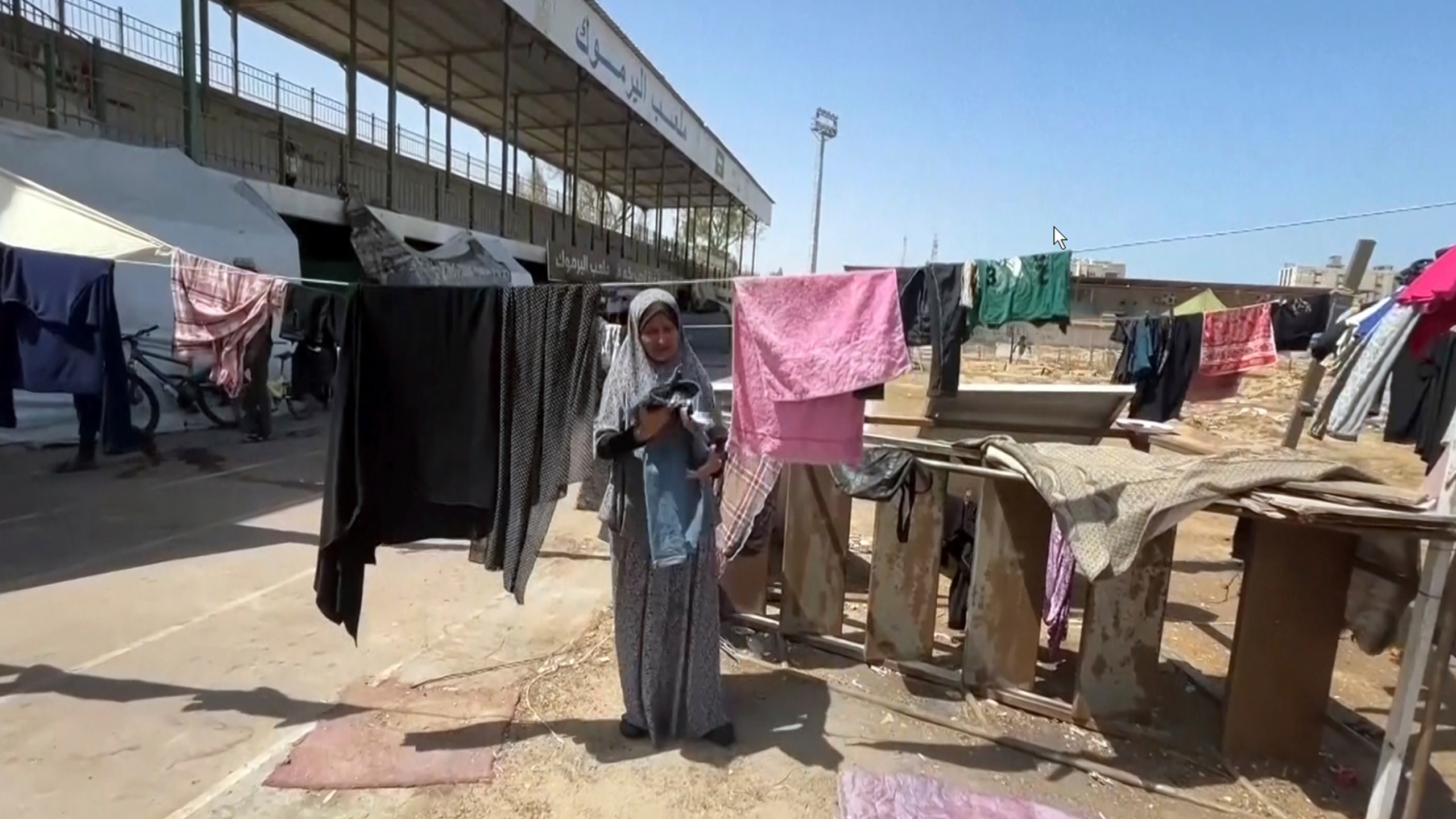 This image from video shows a woman drying clothes, Friday, July 5, 2024 in Gaza City, Gaza Strip. Yarmouk Sports Stadium, once Gaza's biggest soccer arena, is now sheltering thousands of displaced Palestinians who are scraping by with little food or water. (AP Photo)