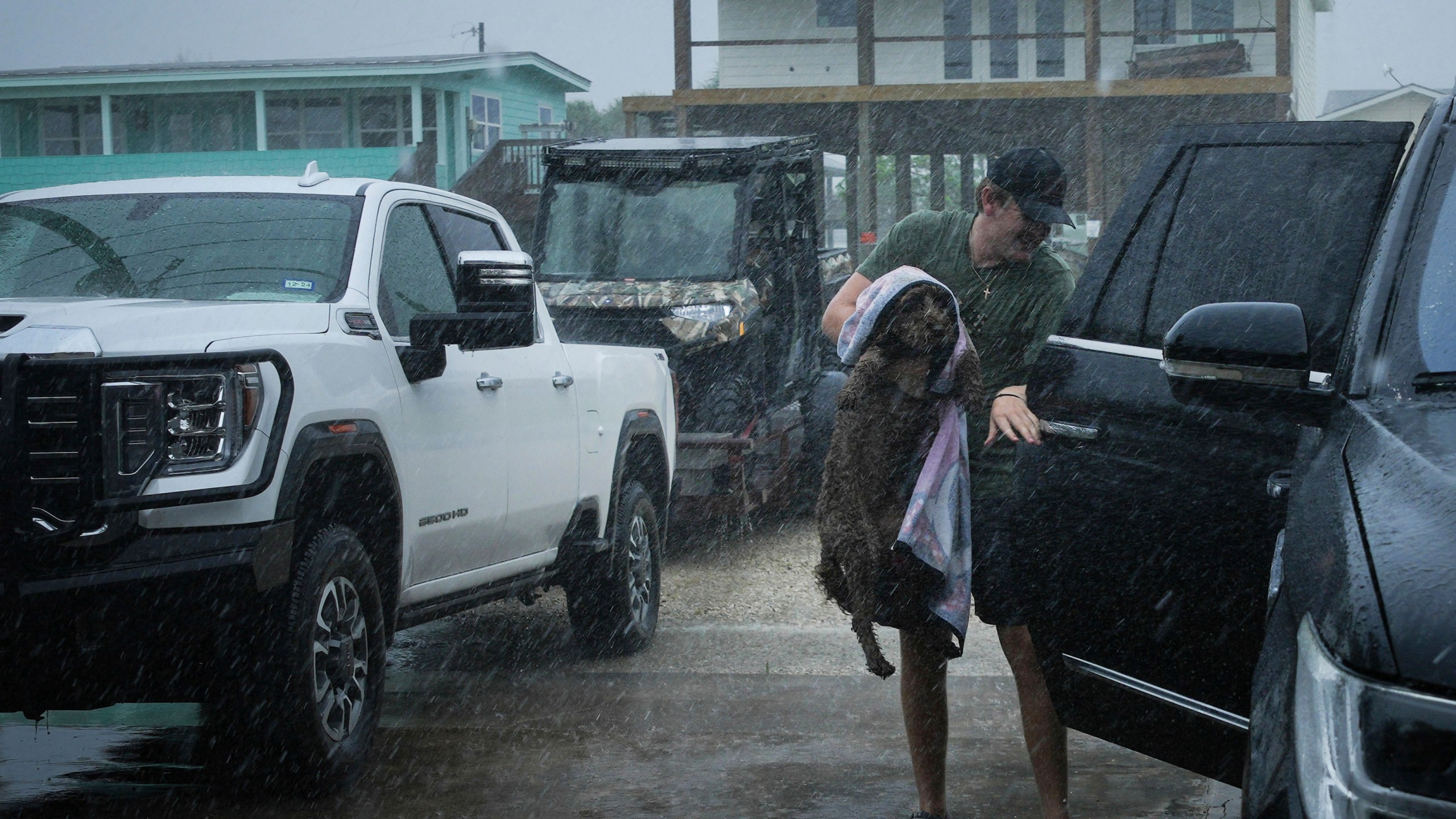 Blake Braun loads his dog Dolly into his family's vehicle as outer bands from Tropical Storm Beryl begin to hit the coast Sunday, July 7, 2024, in Port O'Connor, Texas. (Jon Shapley/Houston Chronicle via AP)