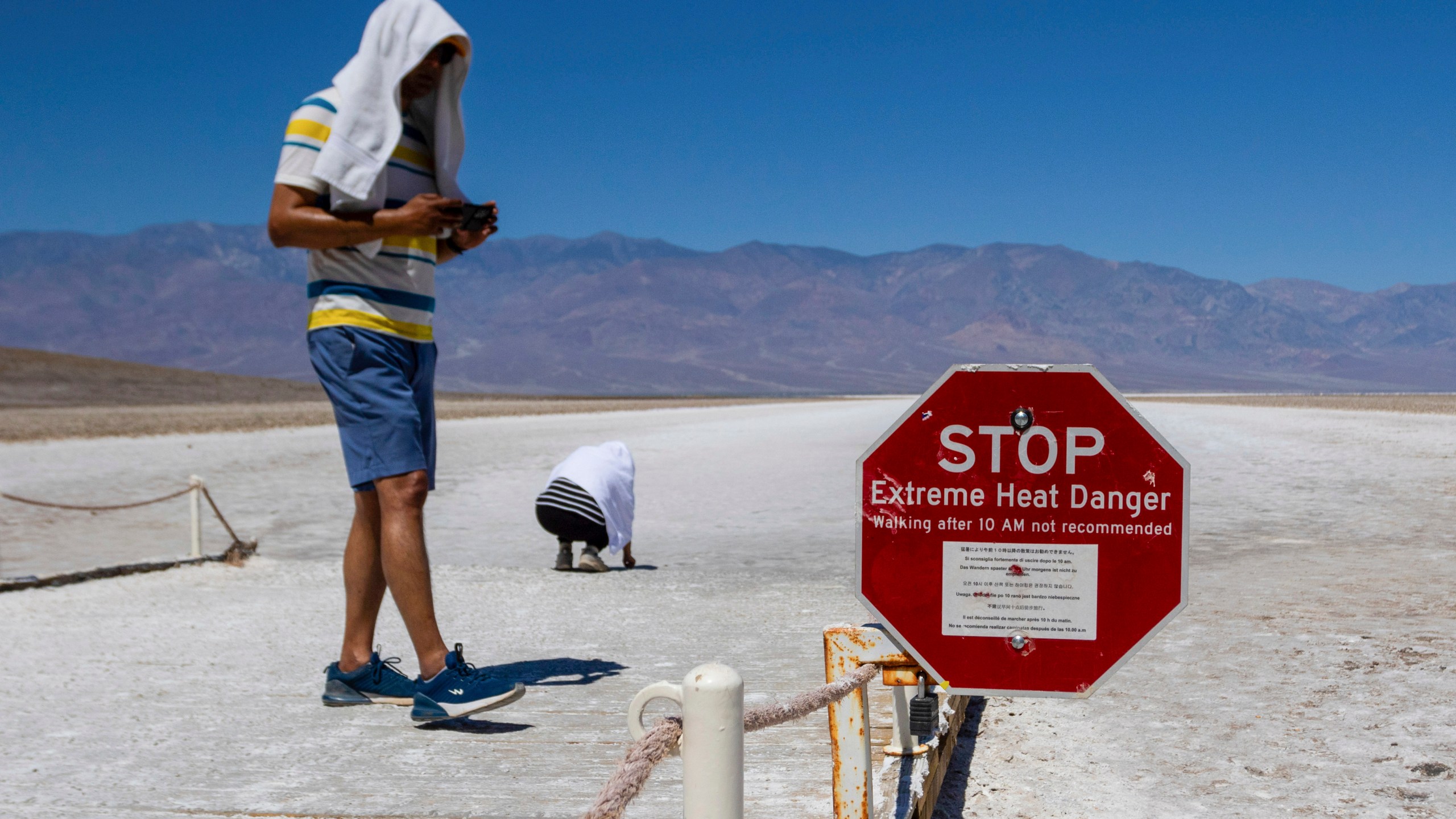 Two people cover themselves in white towels as they walk around Badwater Basin in Death Valley National Park, Calif., Sunday, July 7, 2024. Forecasters say a heat wave could break previous records across the U.S. (AP Photo/Ty ONeil)