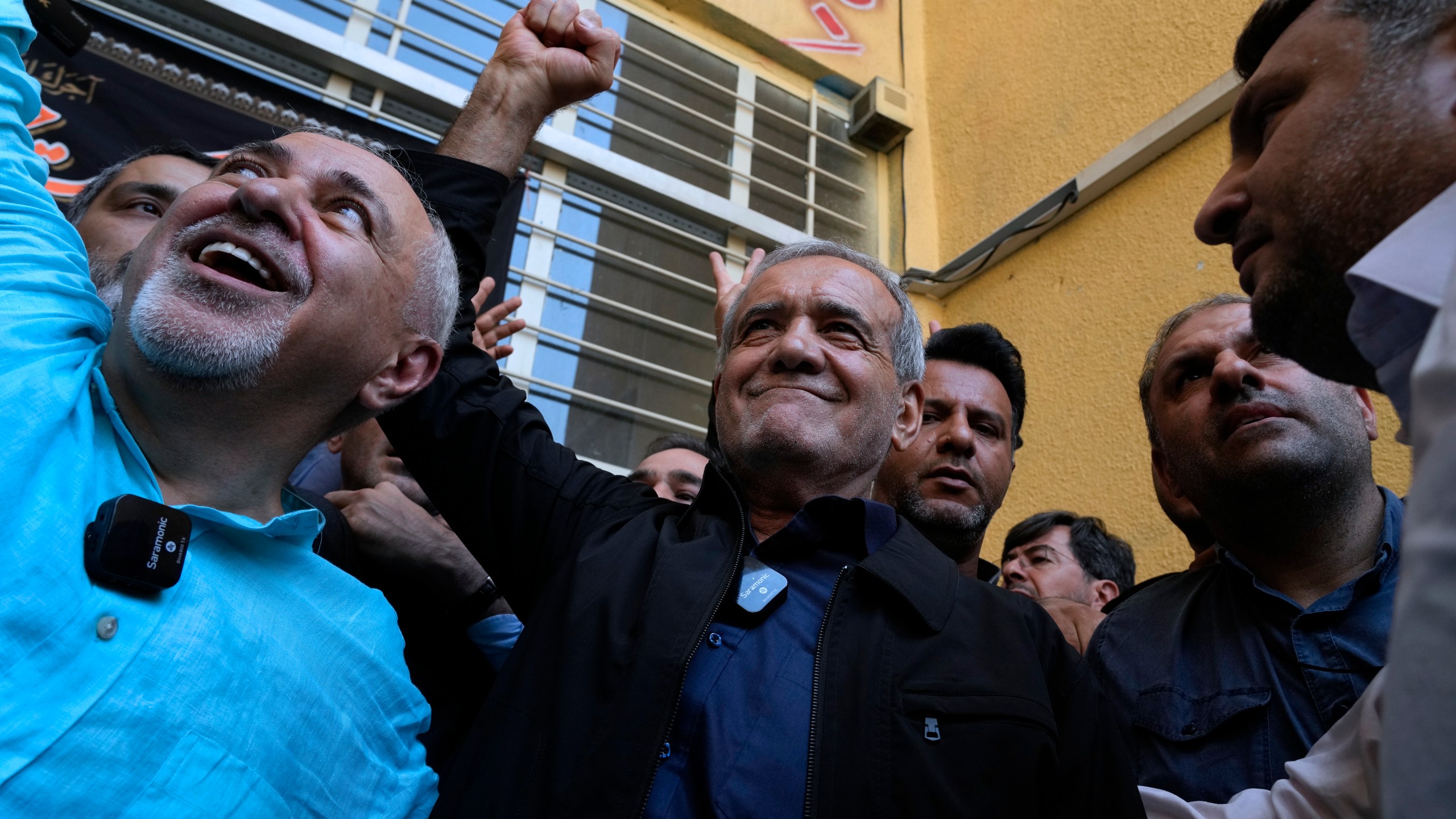 Reformist candidate for the Iran's presidential election Masoud Pezeshkian clenches his fist after casting his vote as he is accompanied by former Foreign Minister Mohammad Javad Zarif, left, at a polling station in Shahr-e-Qods near Tehran, Iran, Friday, July 5, 2024. Iranians are voting in a runoff election to replace the late President Ebrahim Raisi, who was killed in a May helicopter crash in the country’s northwest along with the foreign minister and several other officials. (AP Photo/Vahid Salemi)