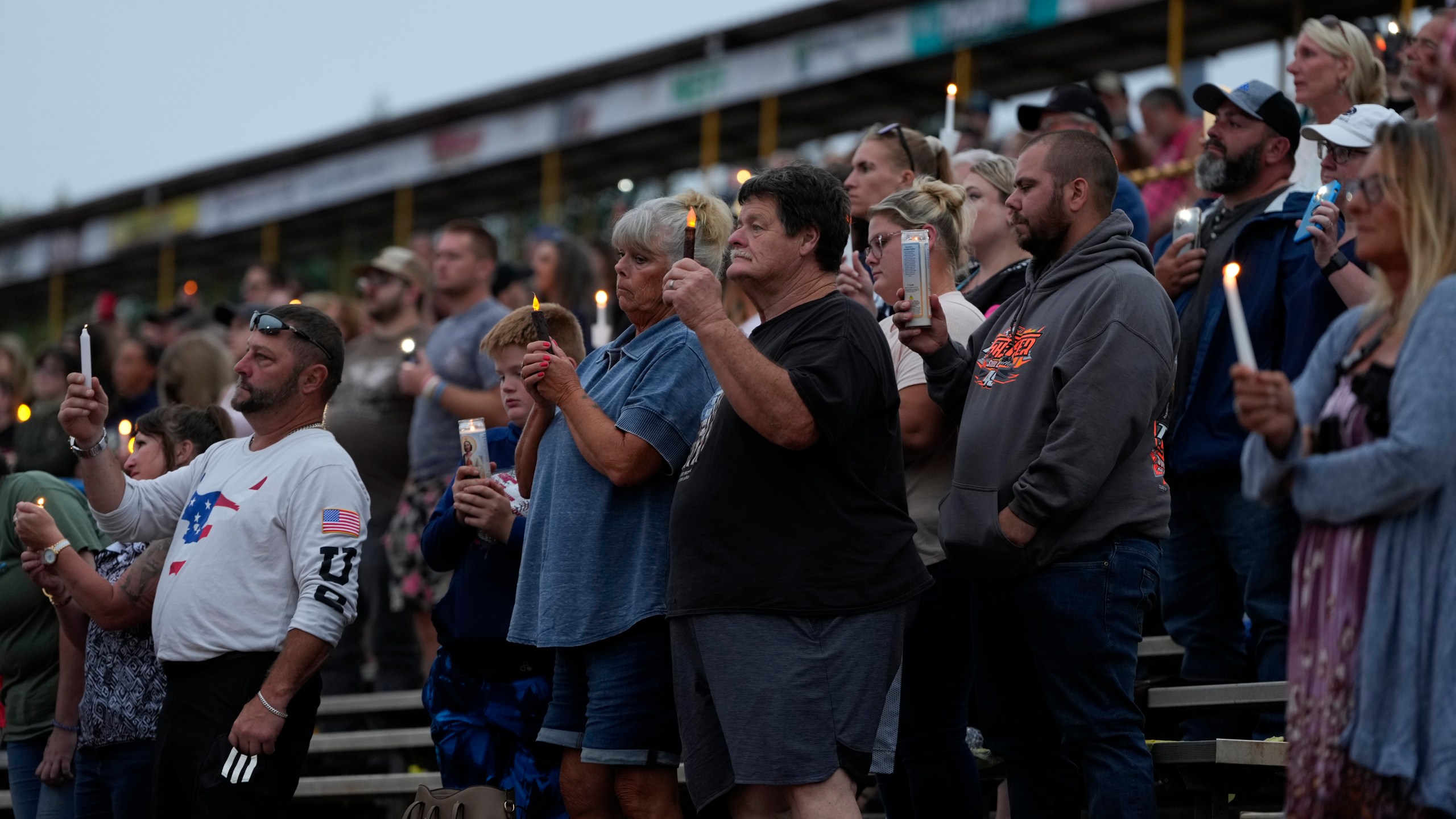 People hold candles and light during a vigil for Corey Comperatore, the former fire chief shot and killed at a weekend rally for former President Donald Trump, Wednesday, July 17, 2024, at Lernerville Speedway in Sarver, Pa. (AP Photo/Matt Slocum)