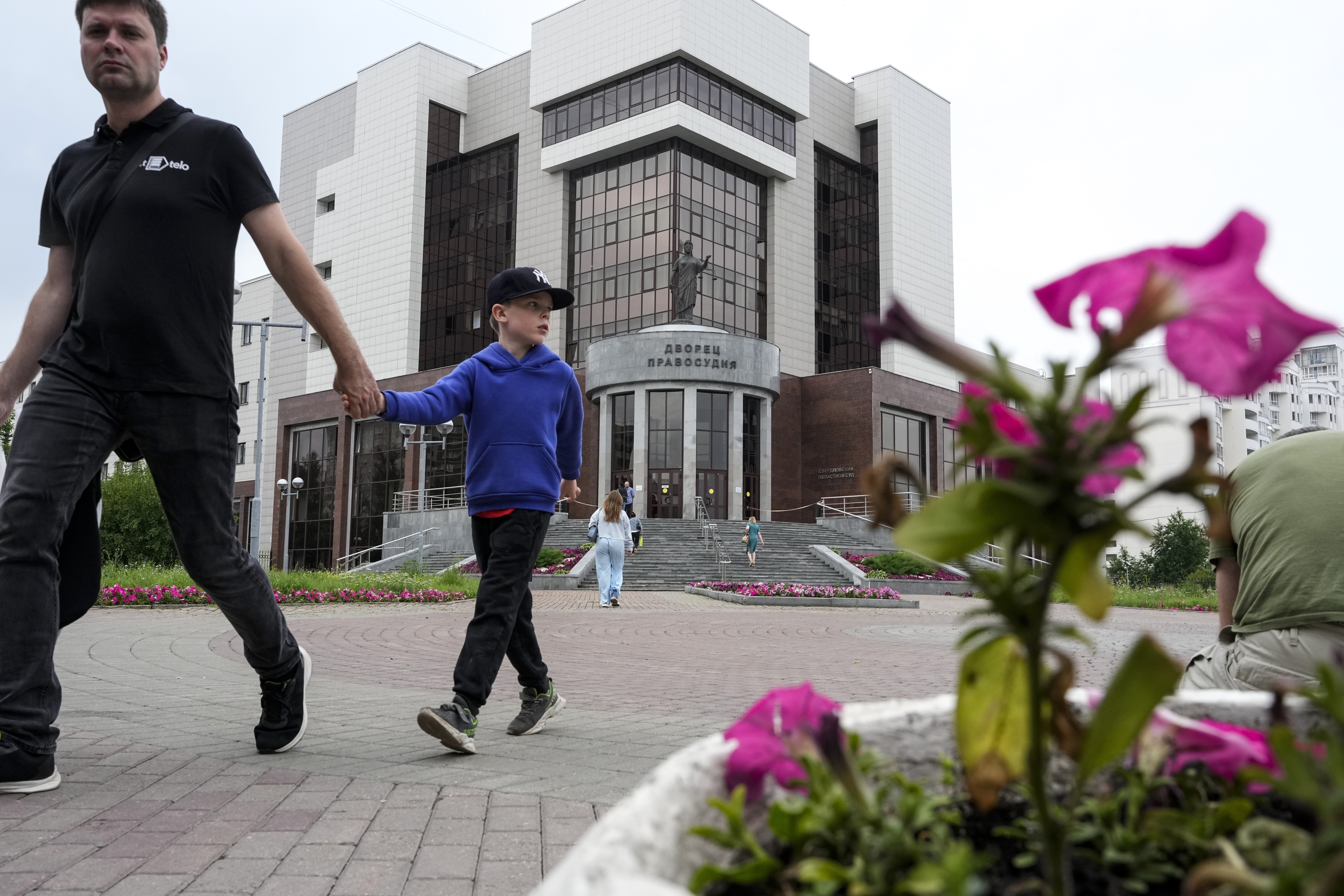 People walk past the court building with the words reading, "Palace of justice," on the front in Yekaterinburg, Russia, Friday, July 19, 2024, prior to the trial of Wall Street Journal reporter Evan Gershkovich's suspected spying activities. (AP Photo/Dmitri Lovetsky)