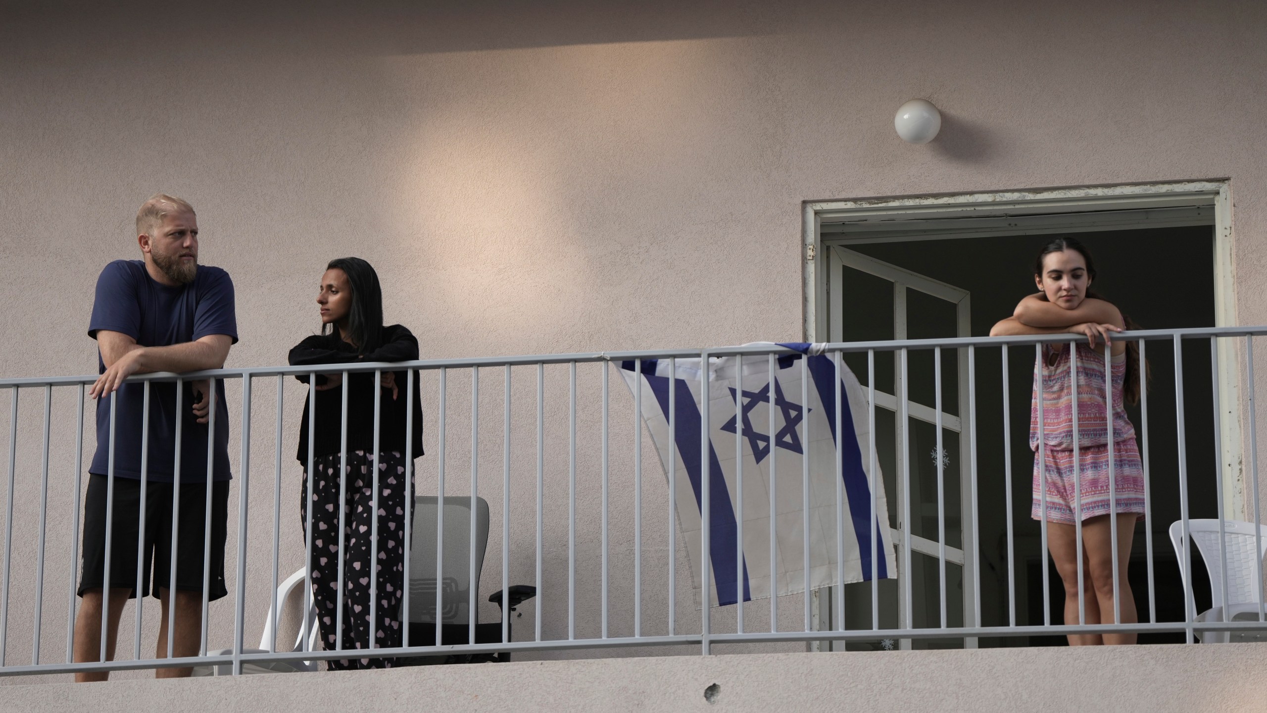 People watch from their balcony as Israeli police investigate the scene of a deadly explosion in Tel Aviv, Israel, Friday, July 19, 2024.(AP Photo/Oded Balilty)