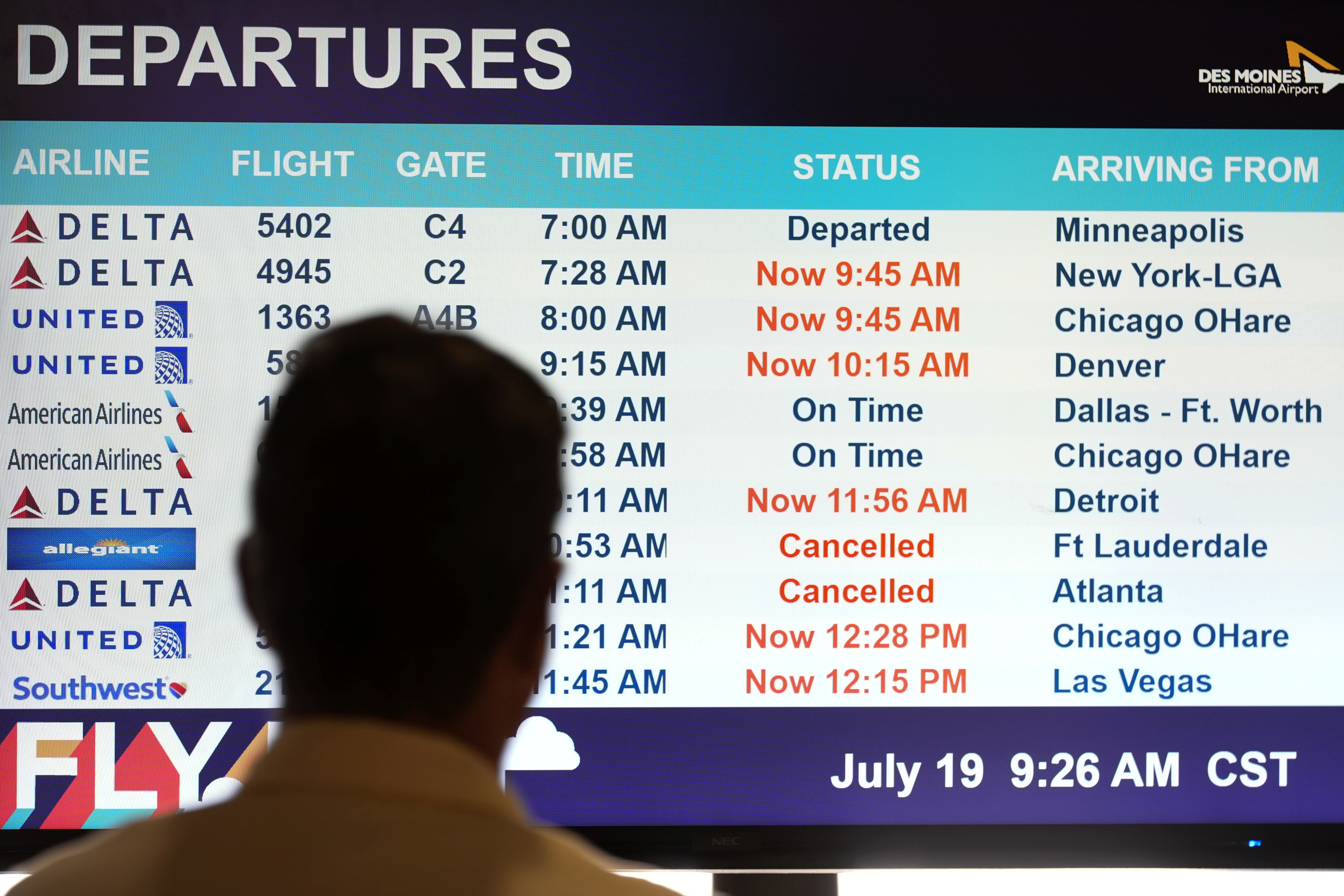 A passenger looks at a departures monitor at the Des Moines International Airport, Friday, July 19, 2024, in Des Moines, Iowa. (AP Photo/Charlie Neibergall)