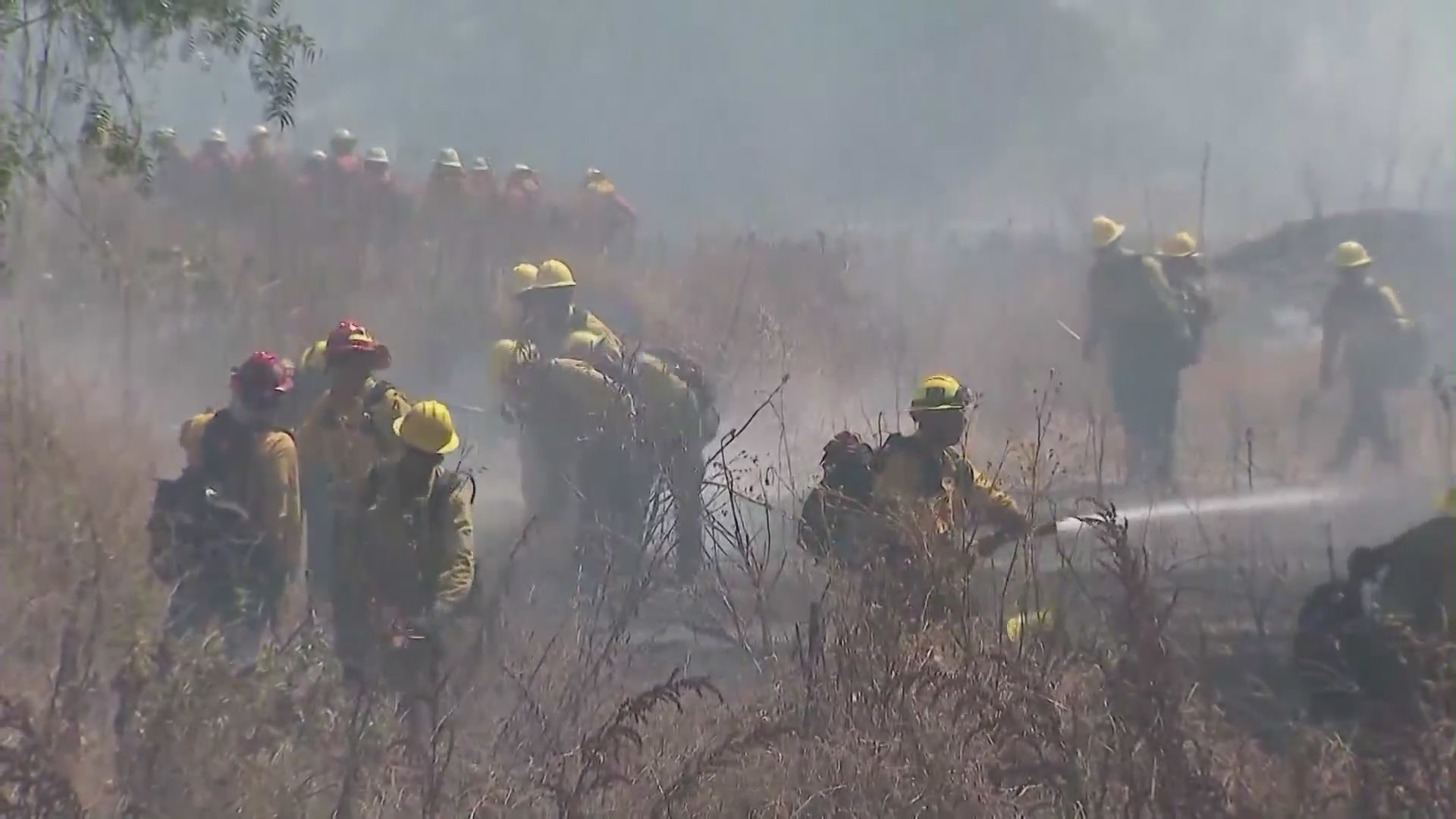 Southern California firefighters battling a brush fire in summer heat. (KTLA)