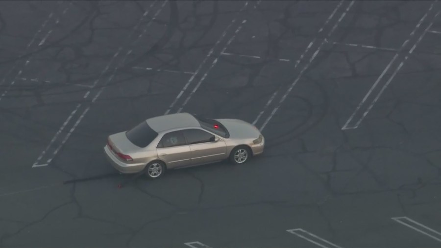 A spike stripe was successfully deployed on the vehicle as the driver continued moving around the parking lot. (KTLA)