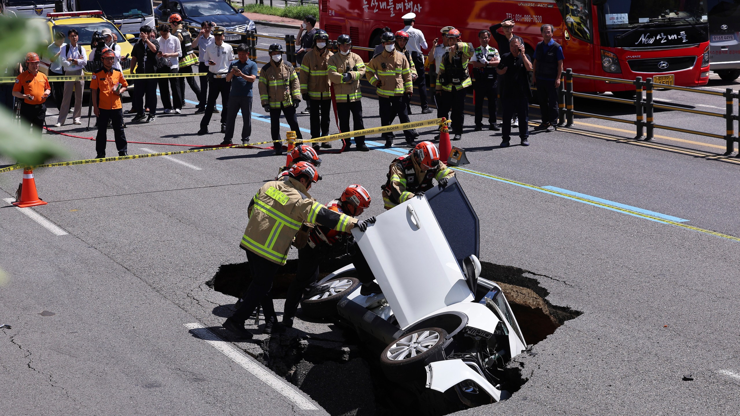 South Korean firefighters check a vehicle that fell into a sinkhole on a street in Seoul, South Korea, Thursday, Aug. 29, 2024. (Seo Dae-yeon/Yonhap via AP)