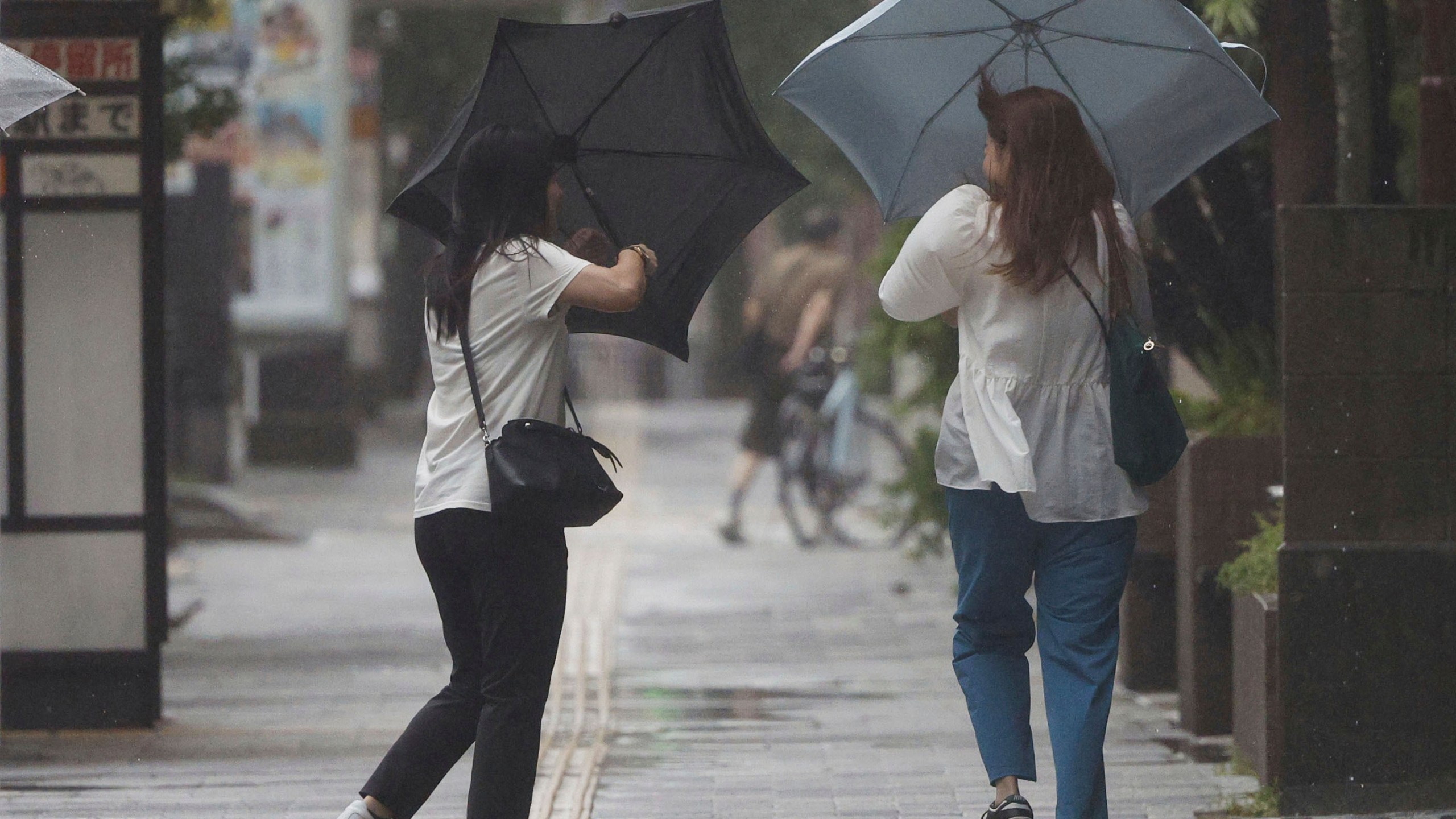 People holding umbrella, struggle with the strong wind as a typhoon is approaching in Kagoshima, western Japan, Thursday, Aug. 29, 2024, (Hidetaka Komukai/Kyodo News via AP)