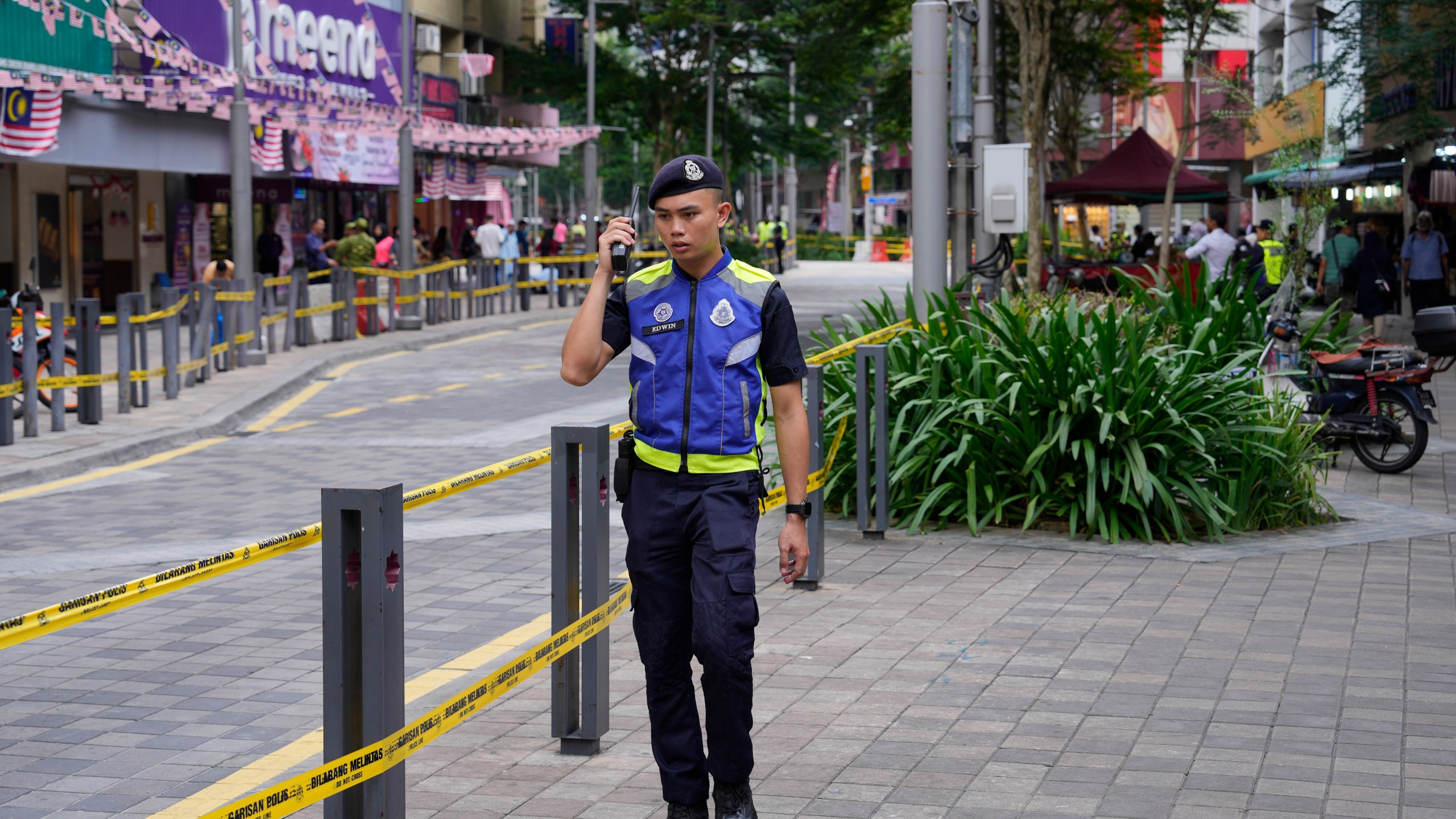 Police stand guard on a closed roadside after another deep sinkhole appeared a week after a woman fell into a sinkhole when a sidewalk caved in in Kuala Lumpur, Thursday, Aug. 29, 2024. (AP Photo/Vincent Thian)