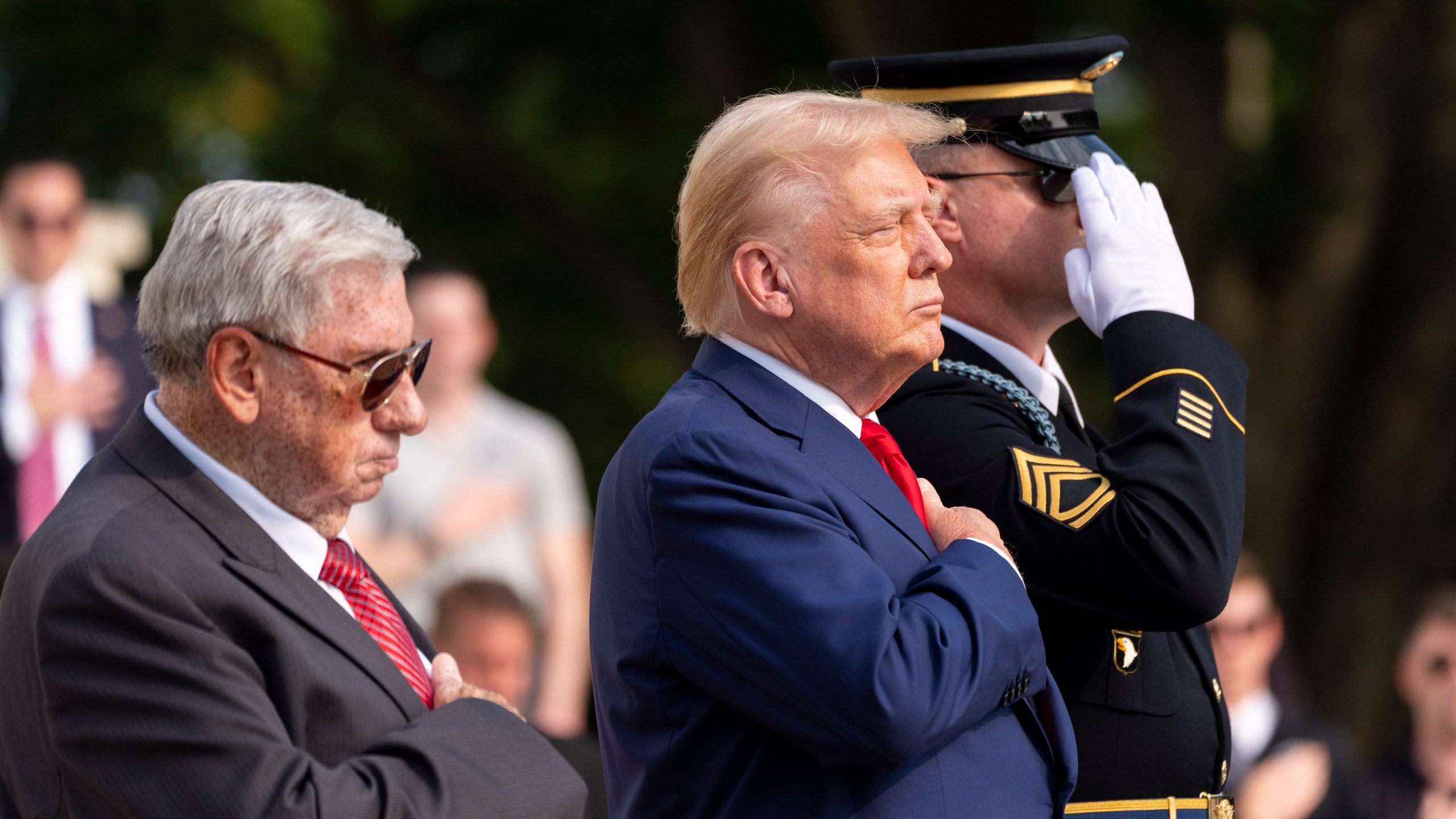 Bill Barnett, left, grandfather of Darin Taylor Hoover, and Republican presidential nominee former President Donald Trump place their hands over their heart after placing a wreath at the Tomb of the Unknown Solider in honor of Staff Sgt. Darin Taylor Hoover at Arlington National Cemetery, Monday, Aug. 26, 2024, in Arlington, Va. (AP Photo/Alex Brandon)